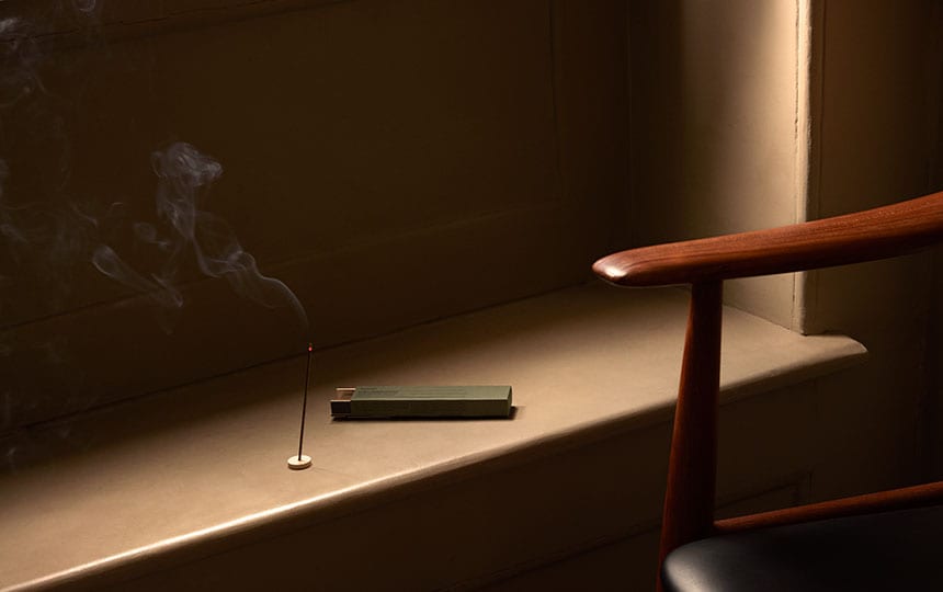 Aesop aromatique incense burning on a brown ledge next to a chair