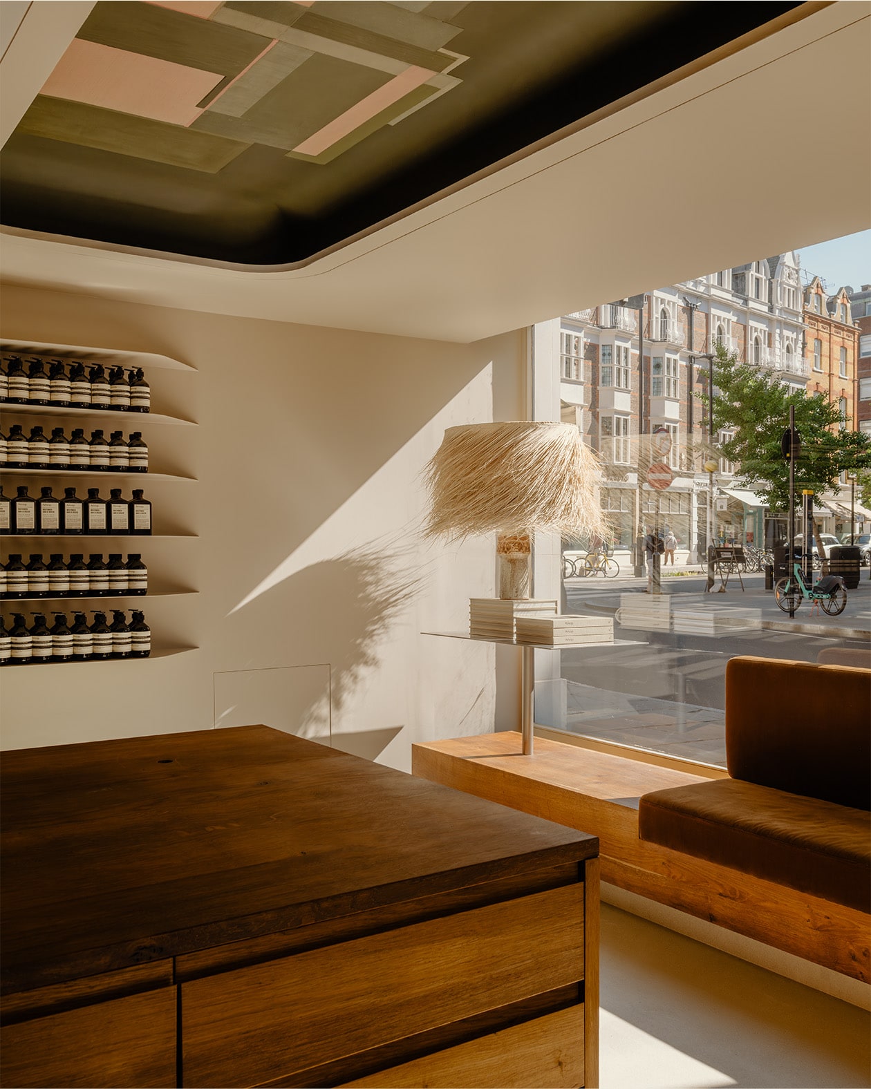 store interior looking out window on street view, with counter top in the foreground, a partial view of a seating area, and a lamp with shaggy shade in the background