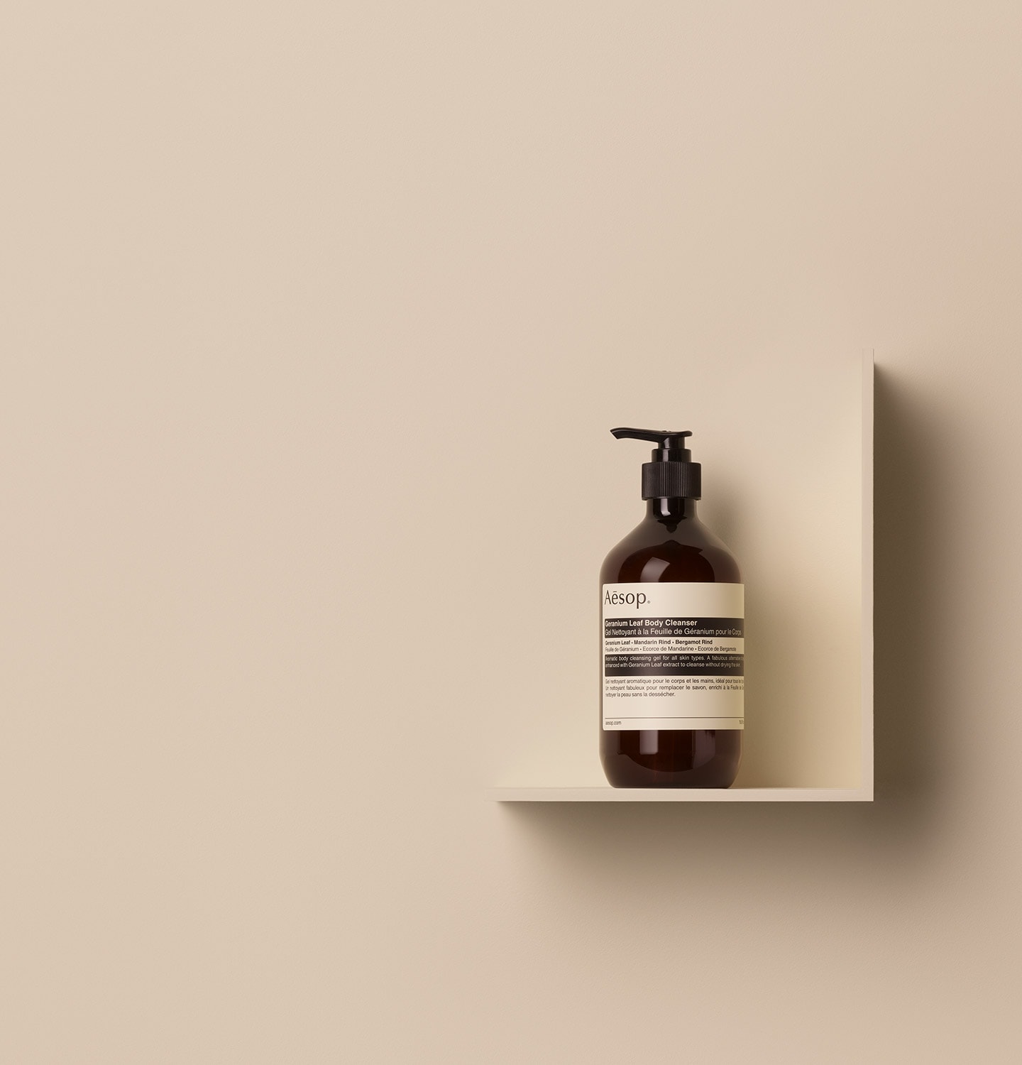 Aesop Geranium Leaf Body Cleanser in 500ml amber pump bottle, placed on a shelf in a beige background