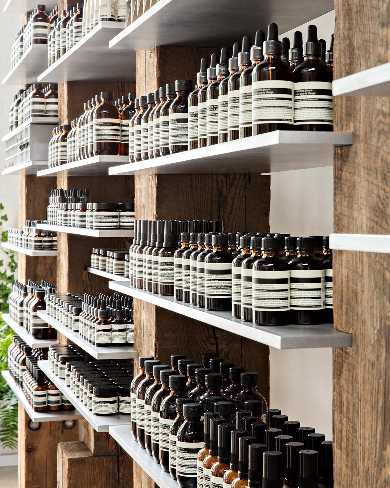 Steel shelving with neatly arranged bottles of Aesop product. 