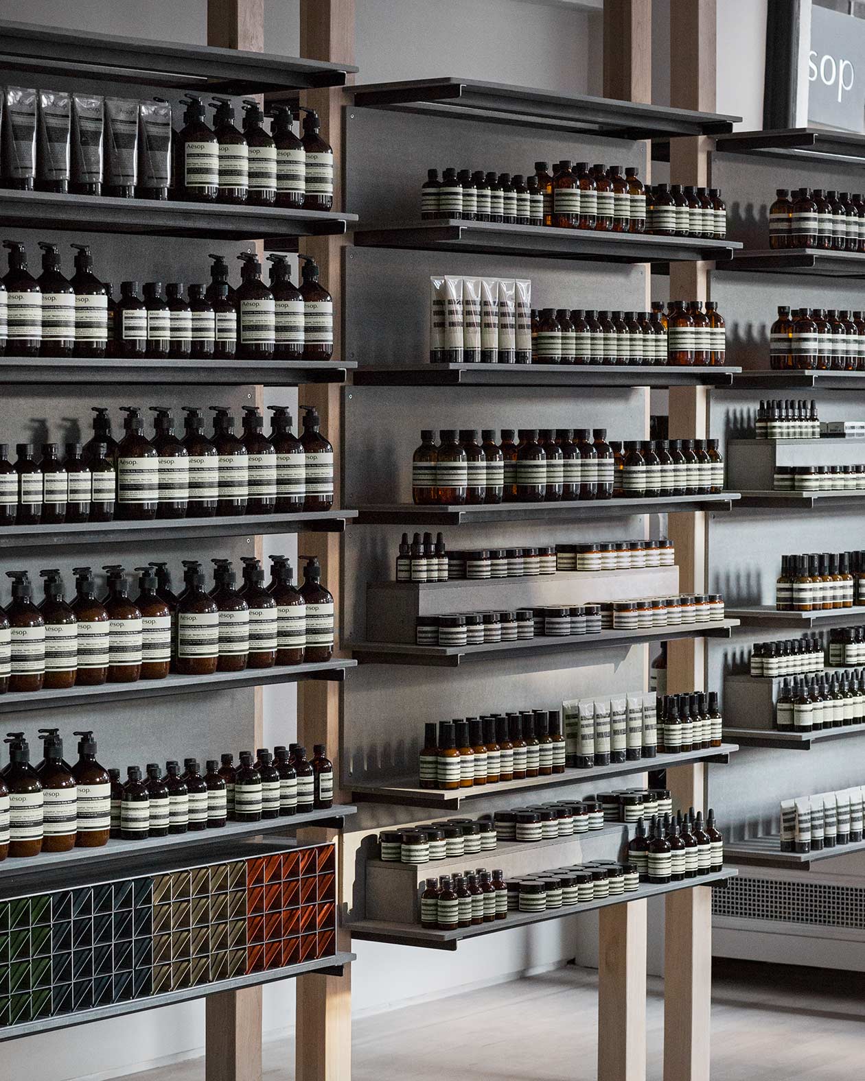 A close-up shot of steel shelving holding rows of Aesop skin care bottles. 
