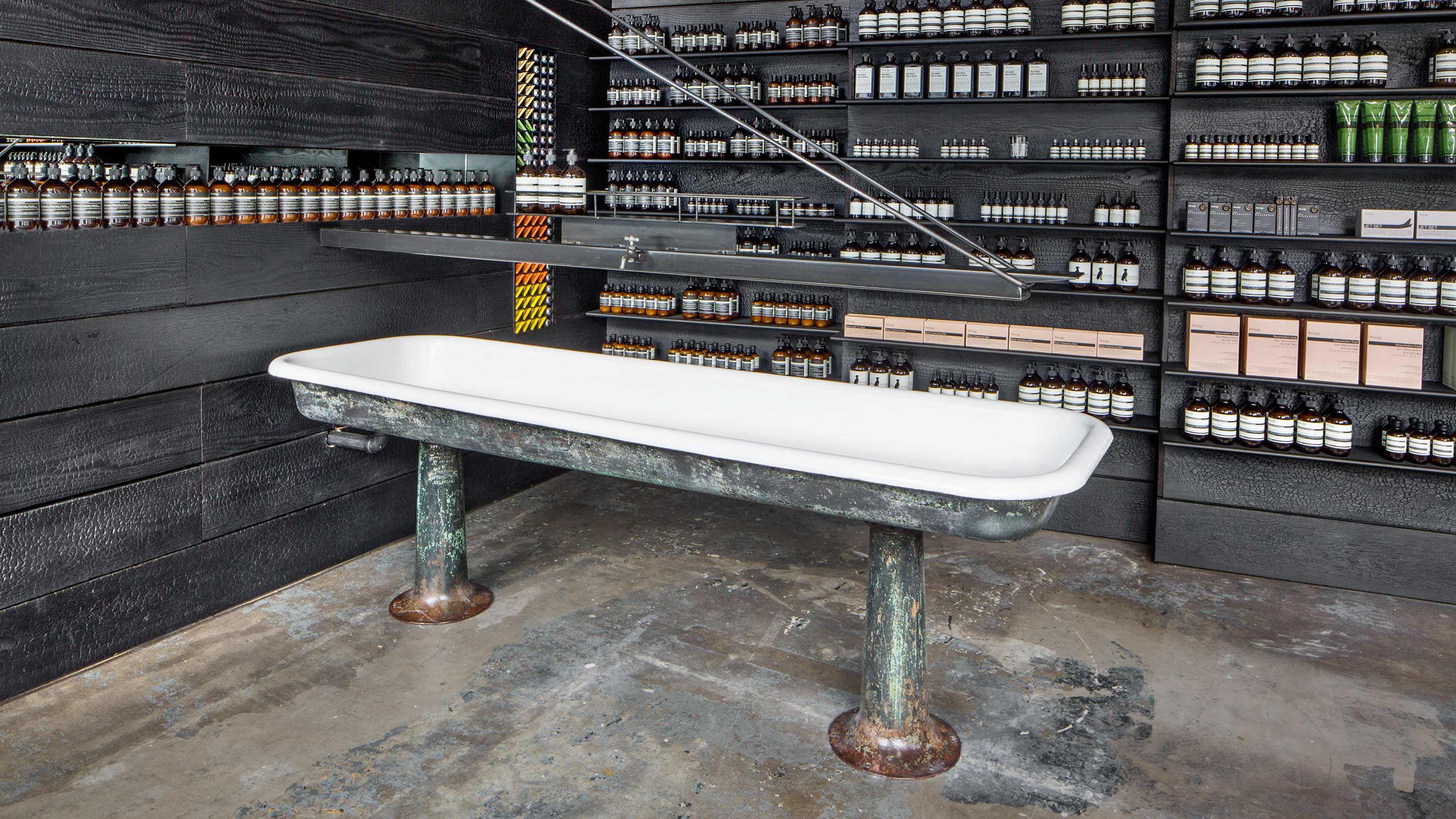 A large vintage basin sits on the store floor at Aesop West End