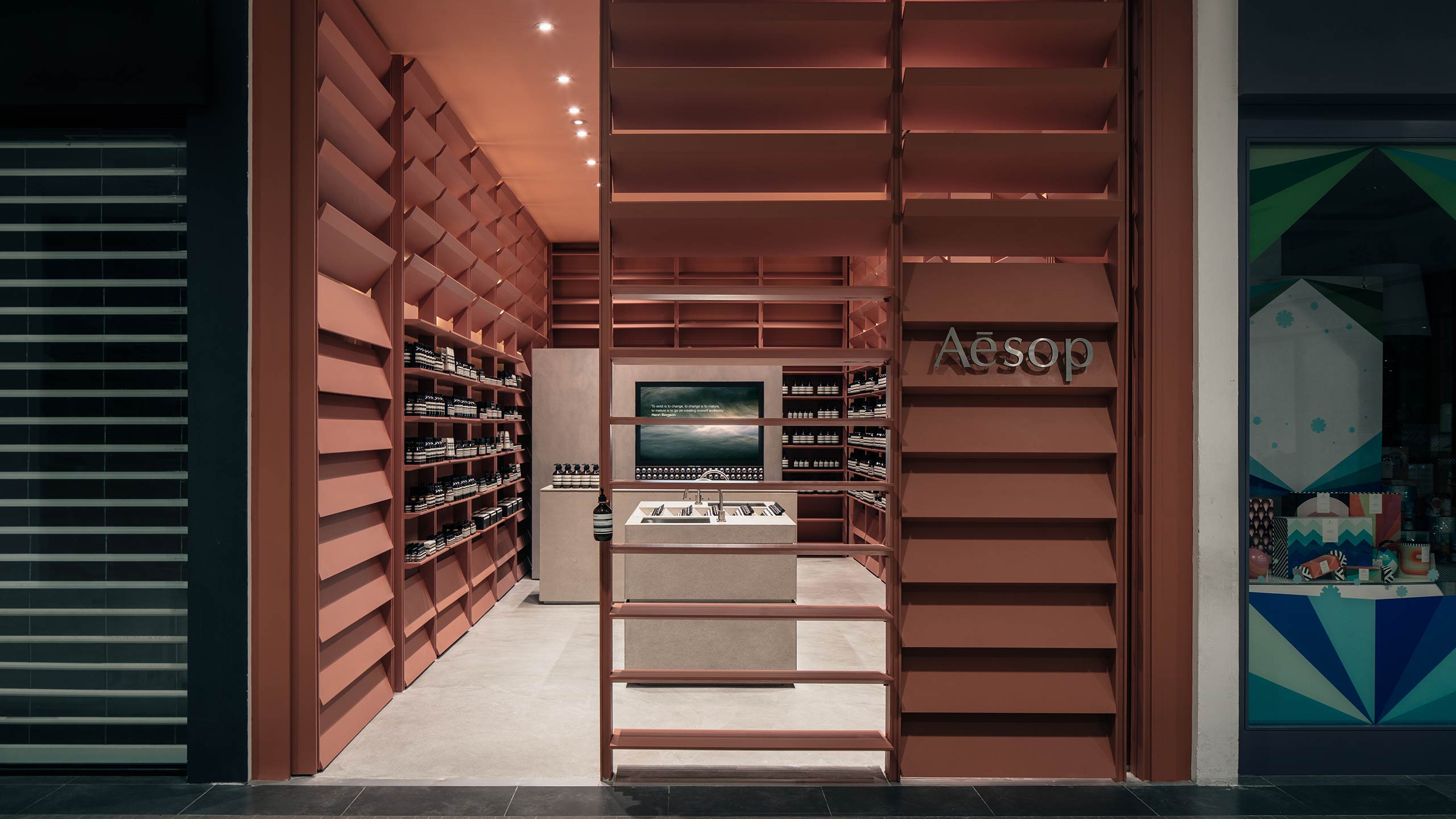 Exterior view of the store showing the blush rose tones of the store and the unique shutter design of the store front.