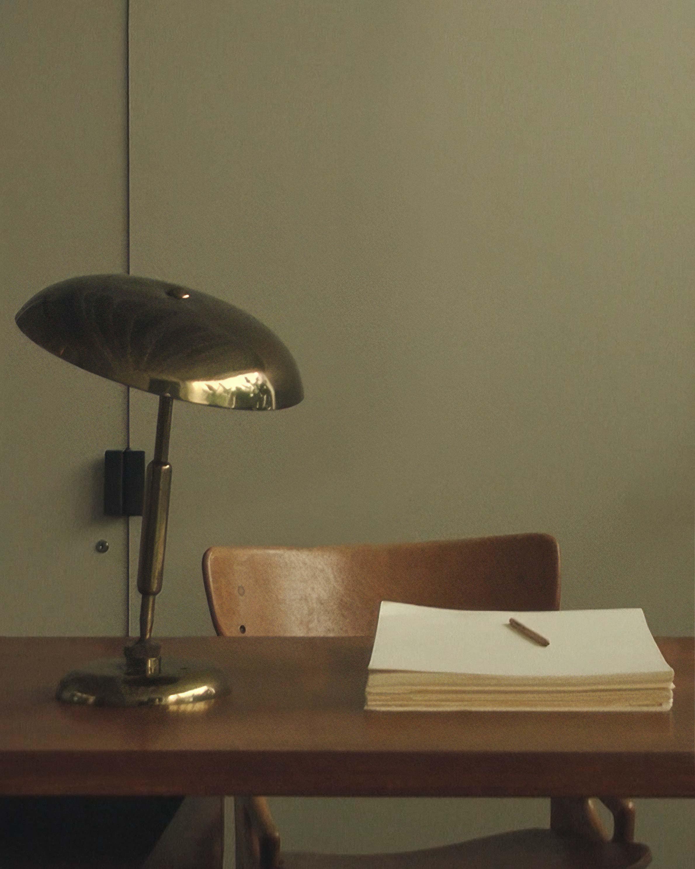 A lamp, papers and a pen placed on a wooden table