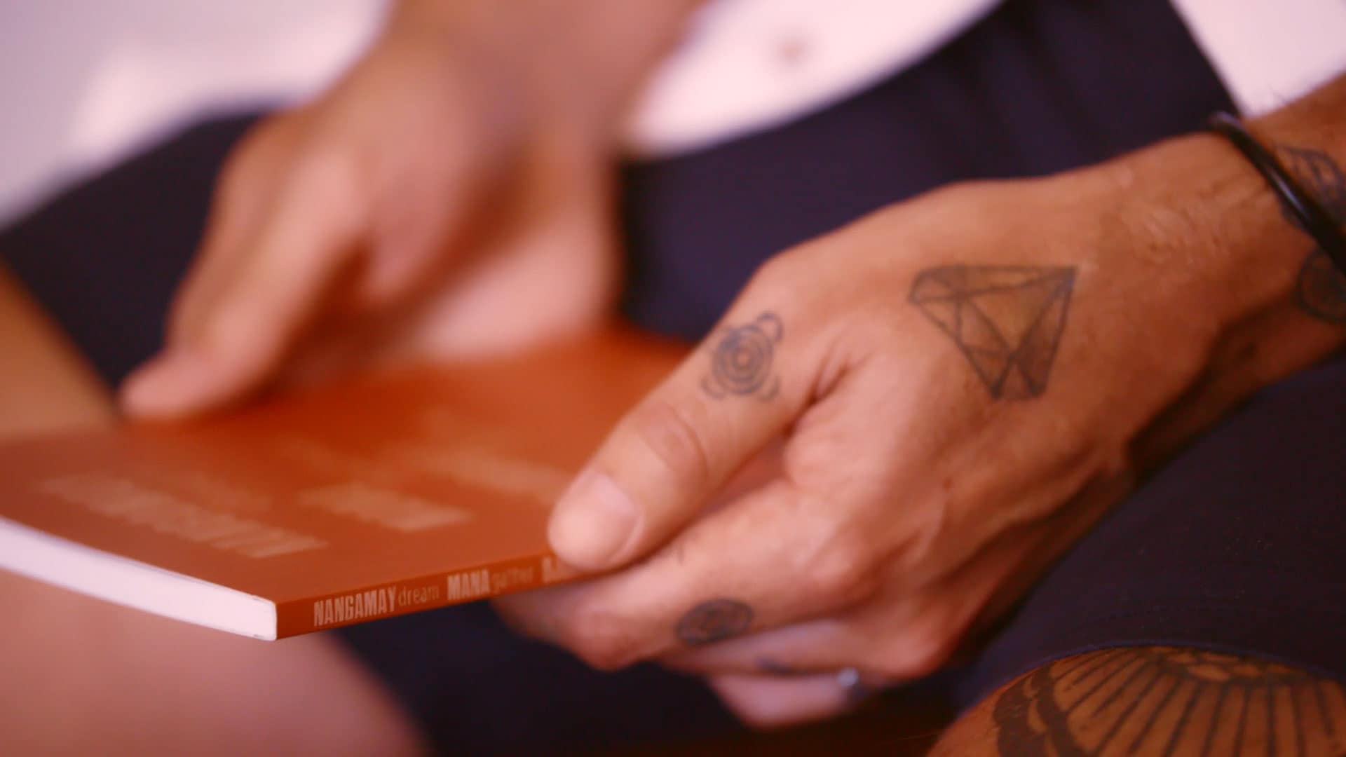 Tattooed hands holding a red book