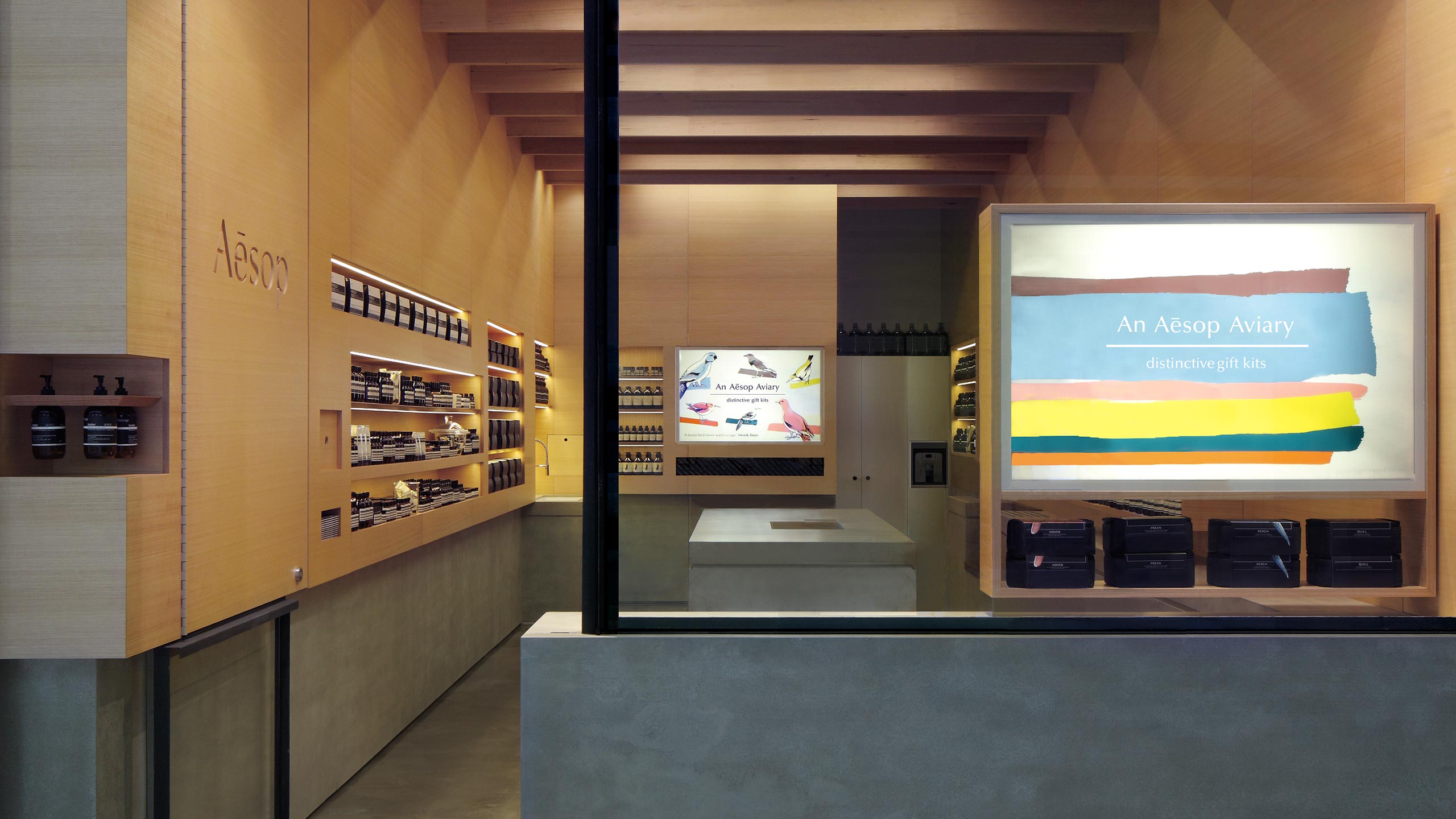 An exterior view of the store, displaying a multi-coloured sign that reads: 'An Aesop Aviary: distinctive gift kits'.