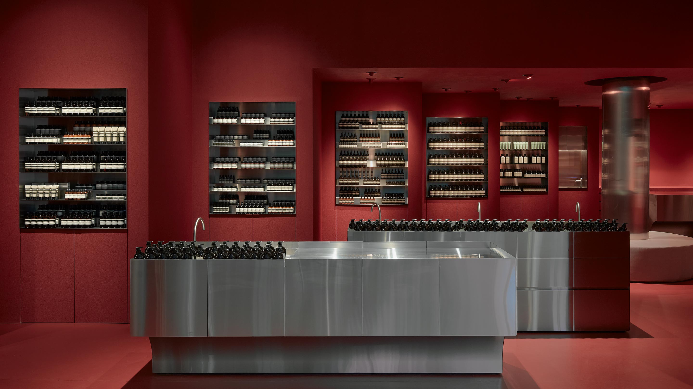 Dark red walls line the interior. Stainless steel basins rest in the centre of the store.