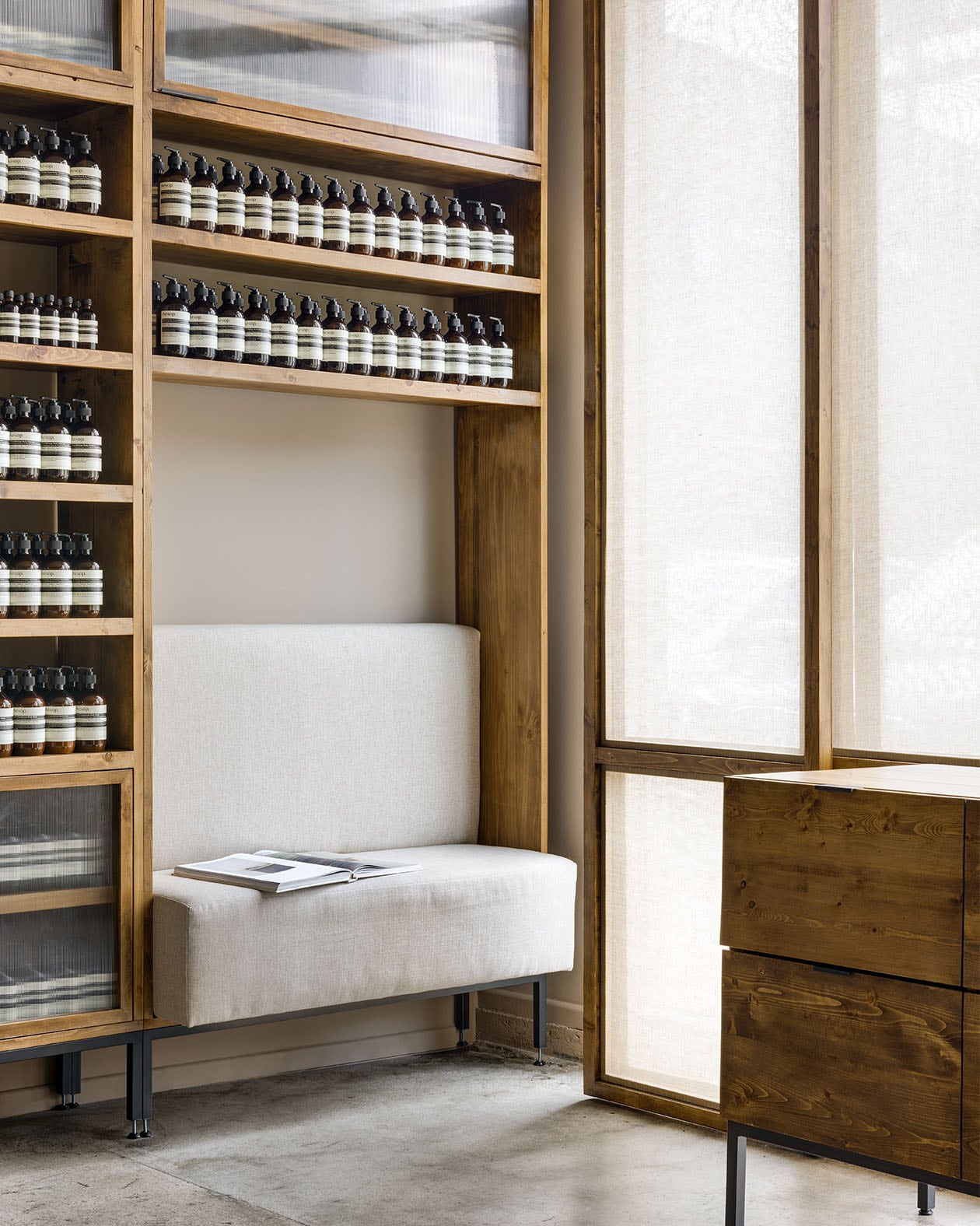 Wooden shelves holding Aesop product; interior seating.