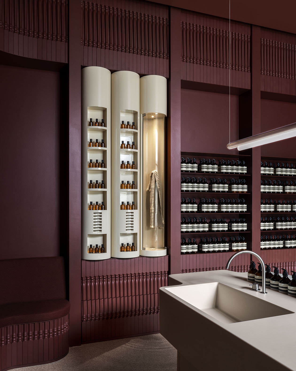 White cylinder shelves sit within a deep plum colored wall