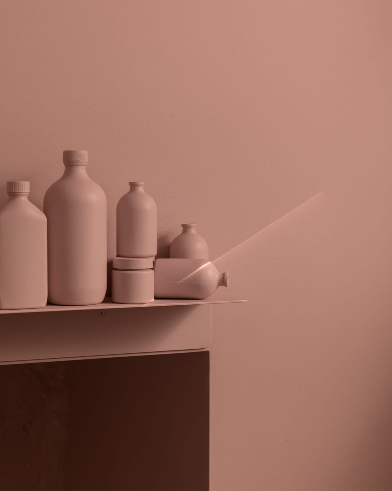 Six prop product containers within the kitchenette section of the store, that have been coloured in the same blush-pink as the surrounding walls.