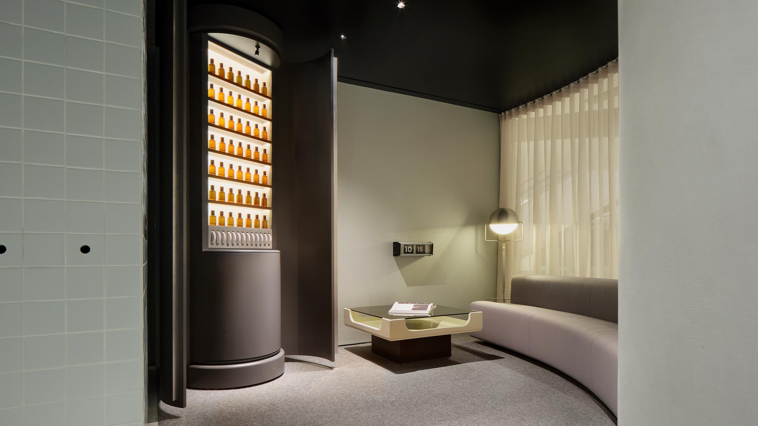 A Fragrance Armoire tucked into a corner next to a cozy couch 