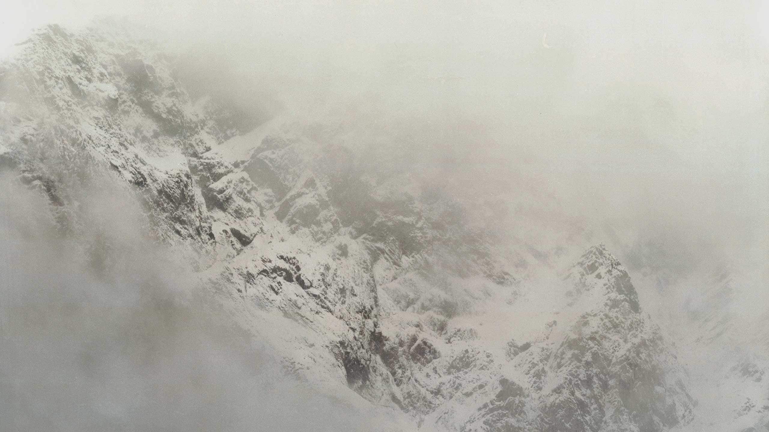 A winter snowy mountain surrounded by fog.