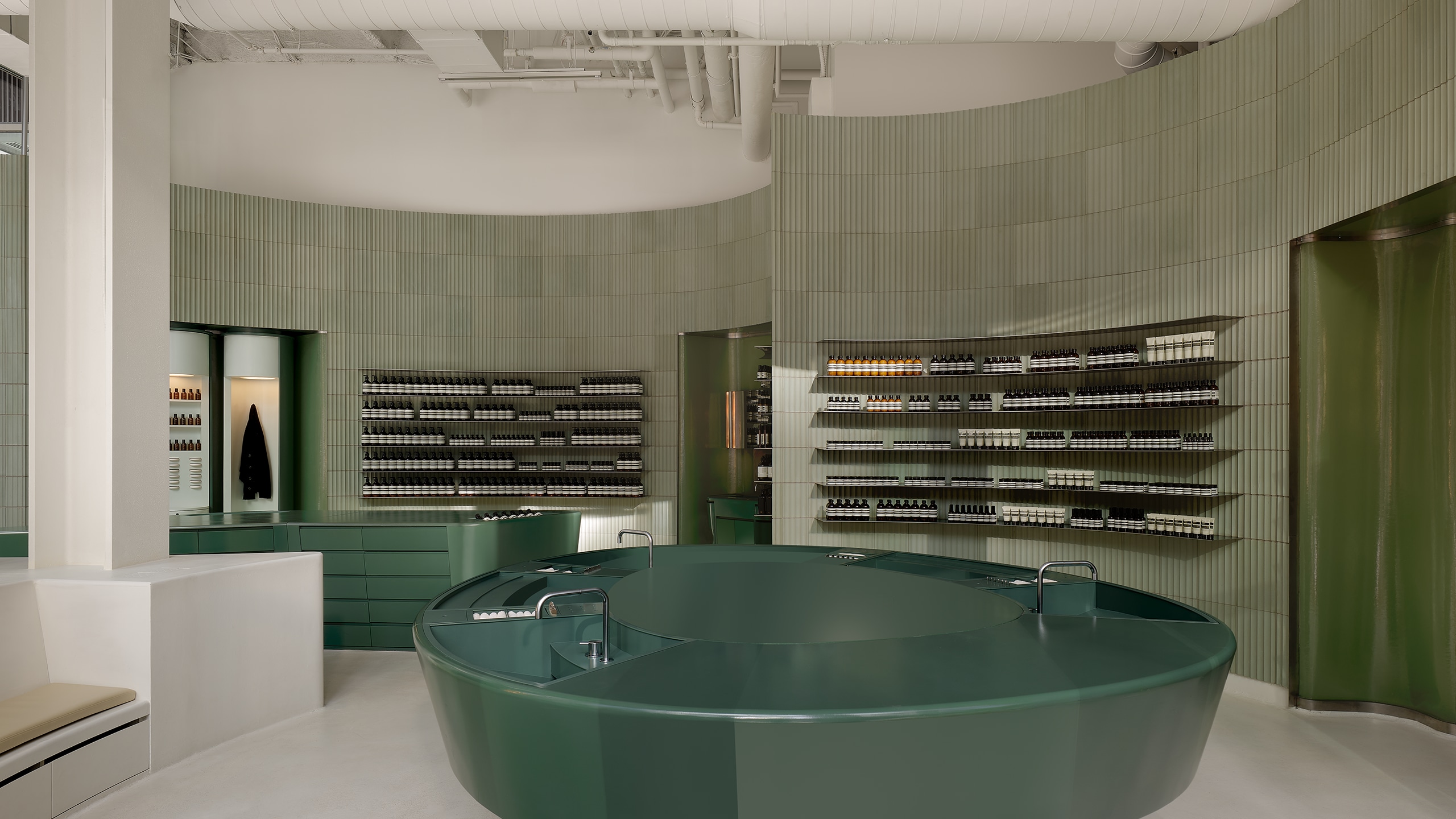 store interior view featuring grey corrugated tile walls lined with products on shelves, and large green basin in the foreground