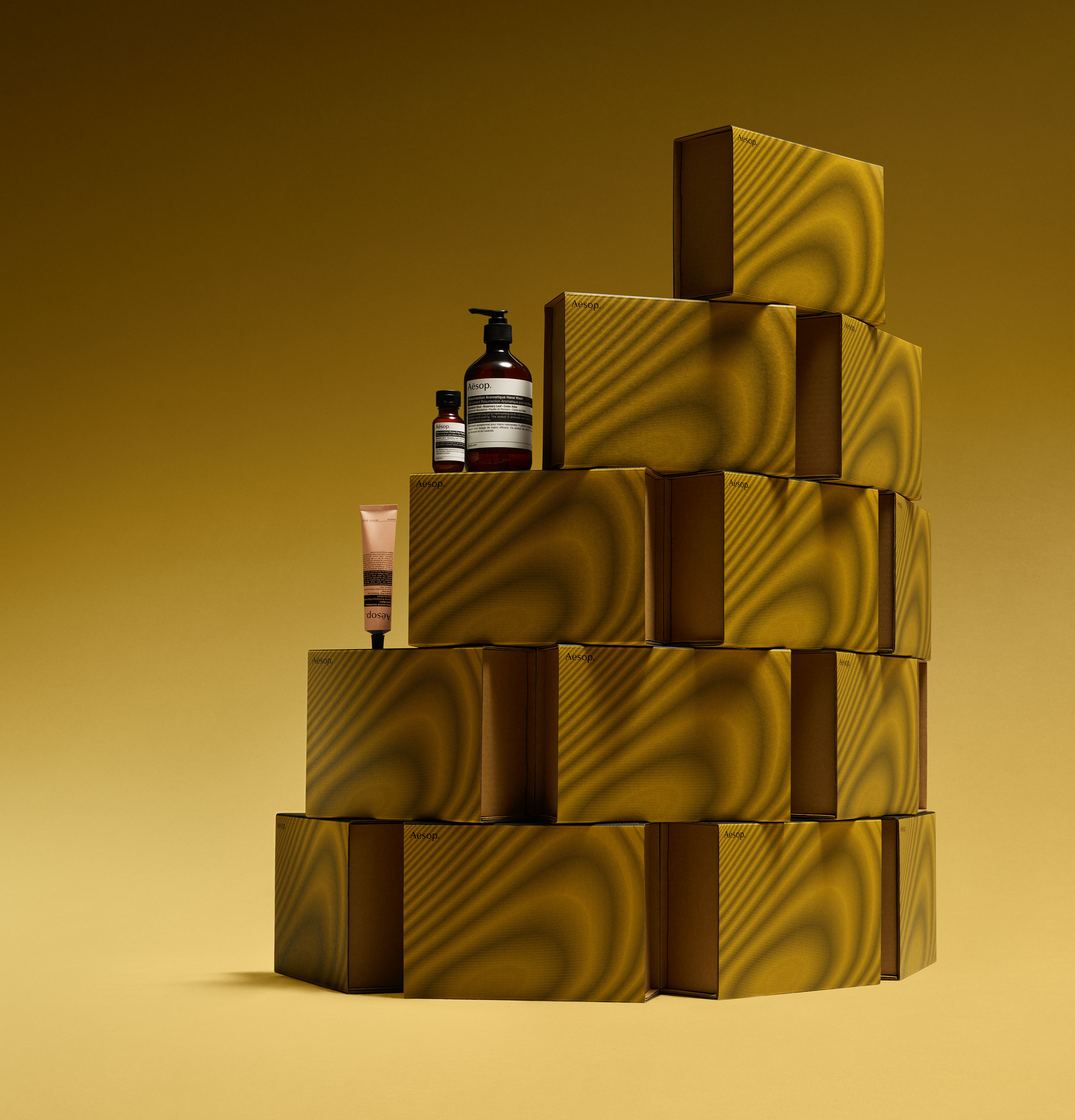 Aesop products placed on stacked mustard yellow cardboard boxes