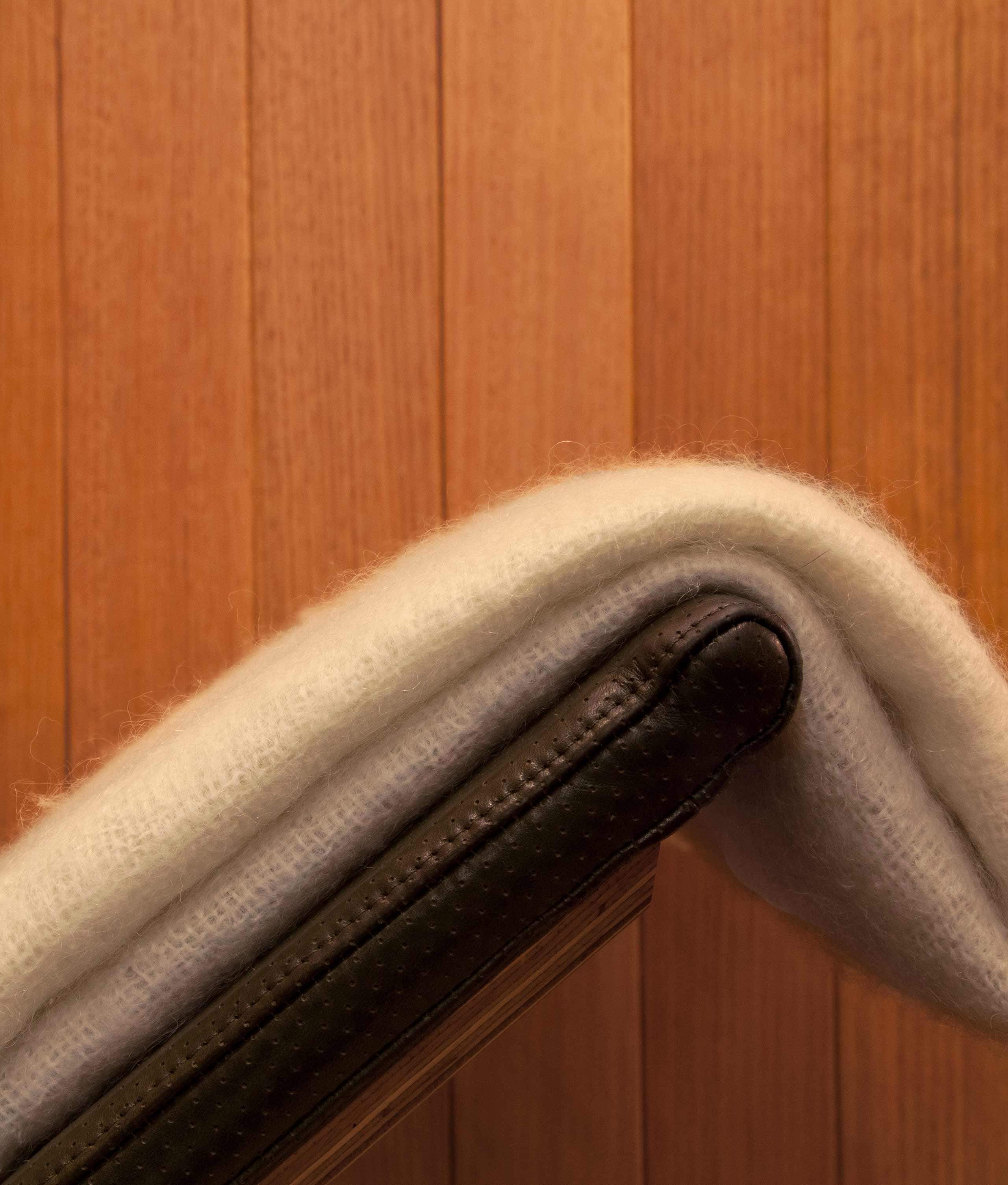 A folded wool blanket placed on a leather chair