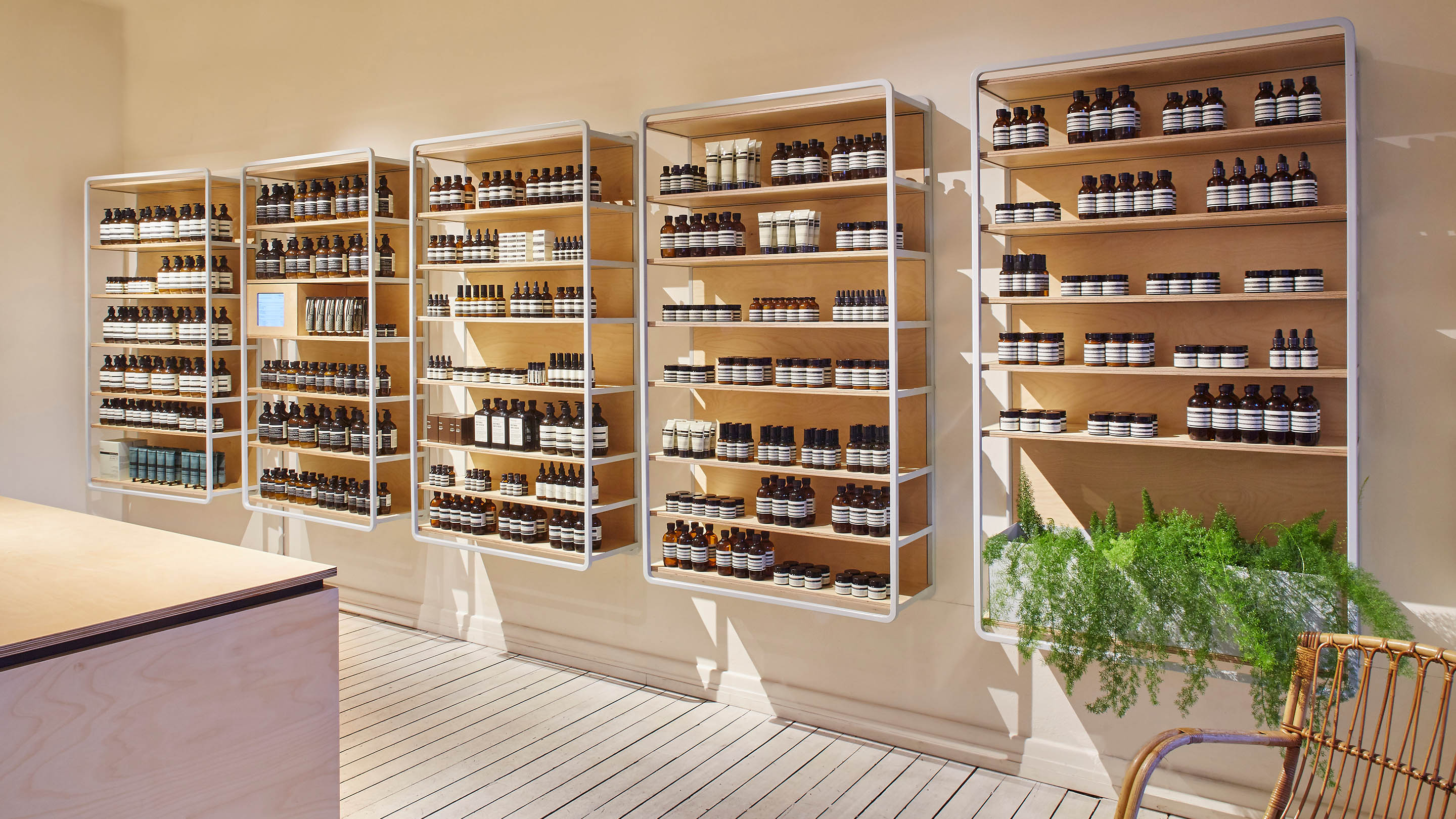 The store displays a bright and sun filled interior. The floor is made from lime-washed timber. A wicker chair is sitting in the corner.