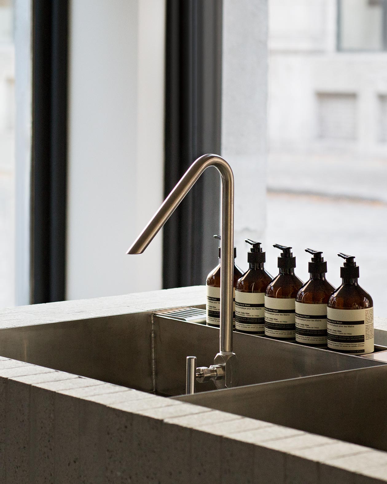 A close-up shot of a sleek and modern shaped tap and basin; featuring Aesop bottles.