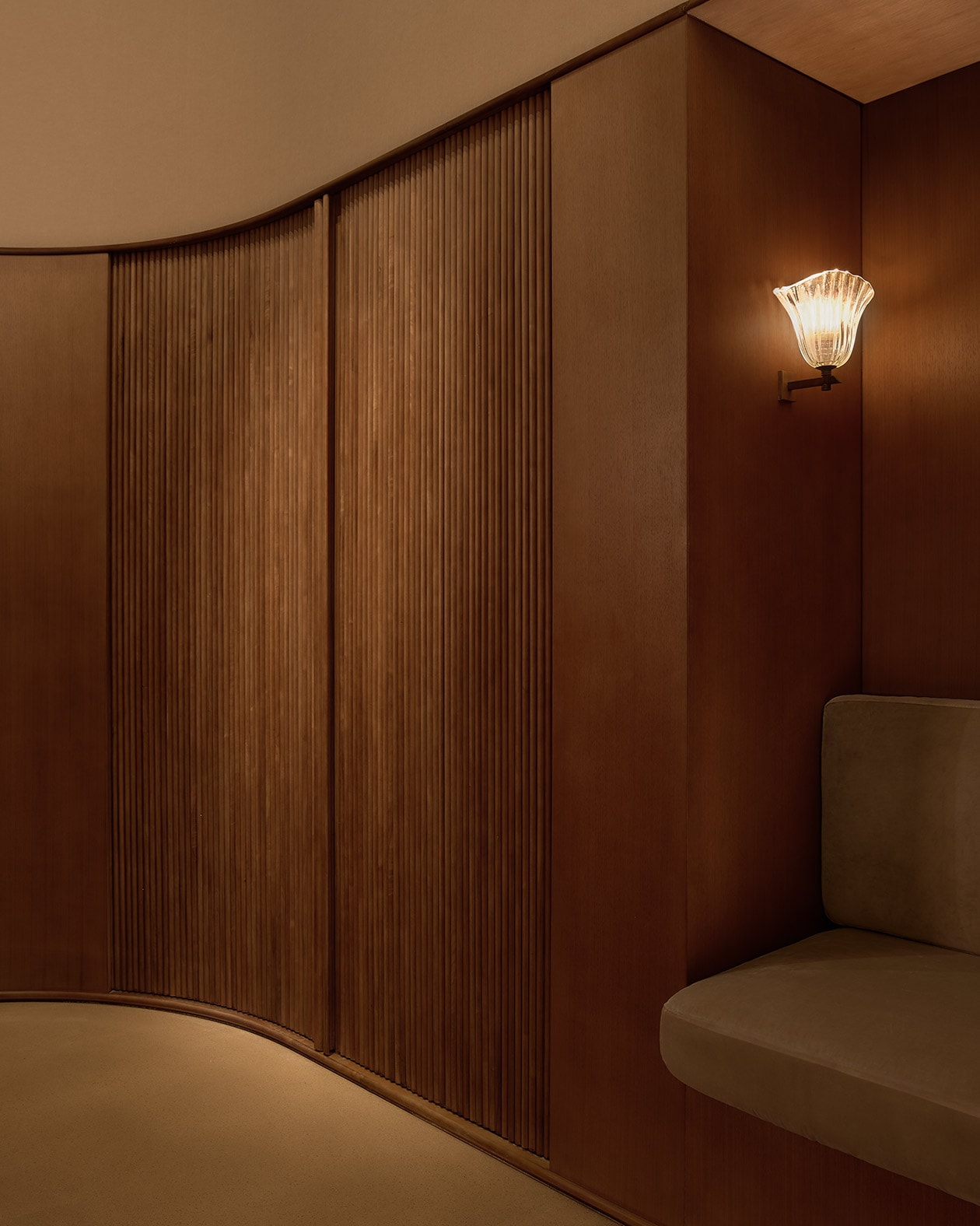 Sheathed in walnut timber cabinetry, with rounded corners and curves that extend up to the ceiling