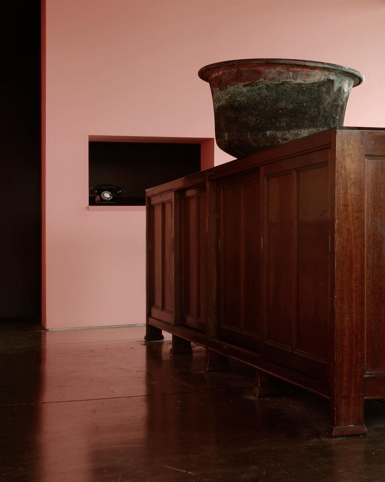 Vintage dark oak cabinet on a mottled concrete floor. A rustic basin rests on top.