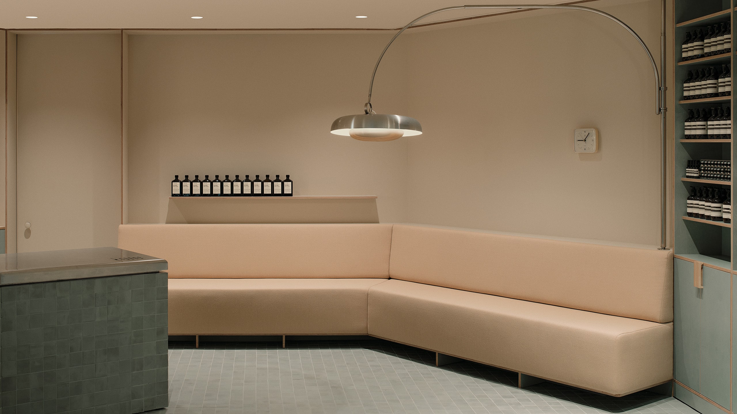A metal lamp hanging over a beige sofa in Aesop Indooroopilly II store