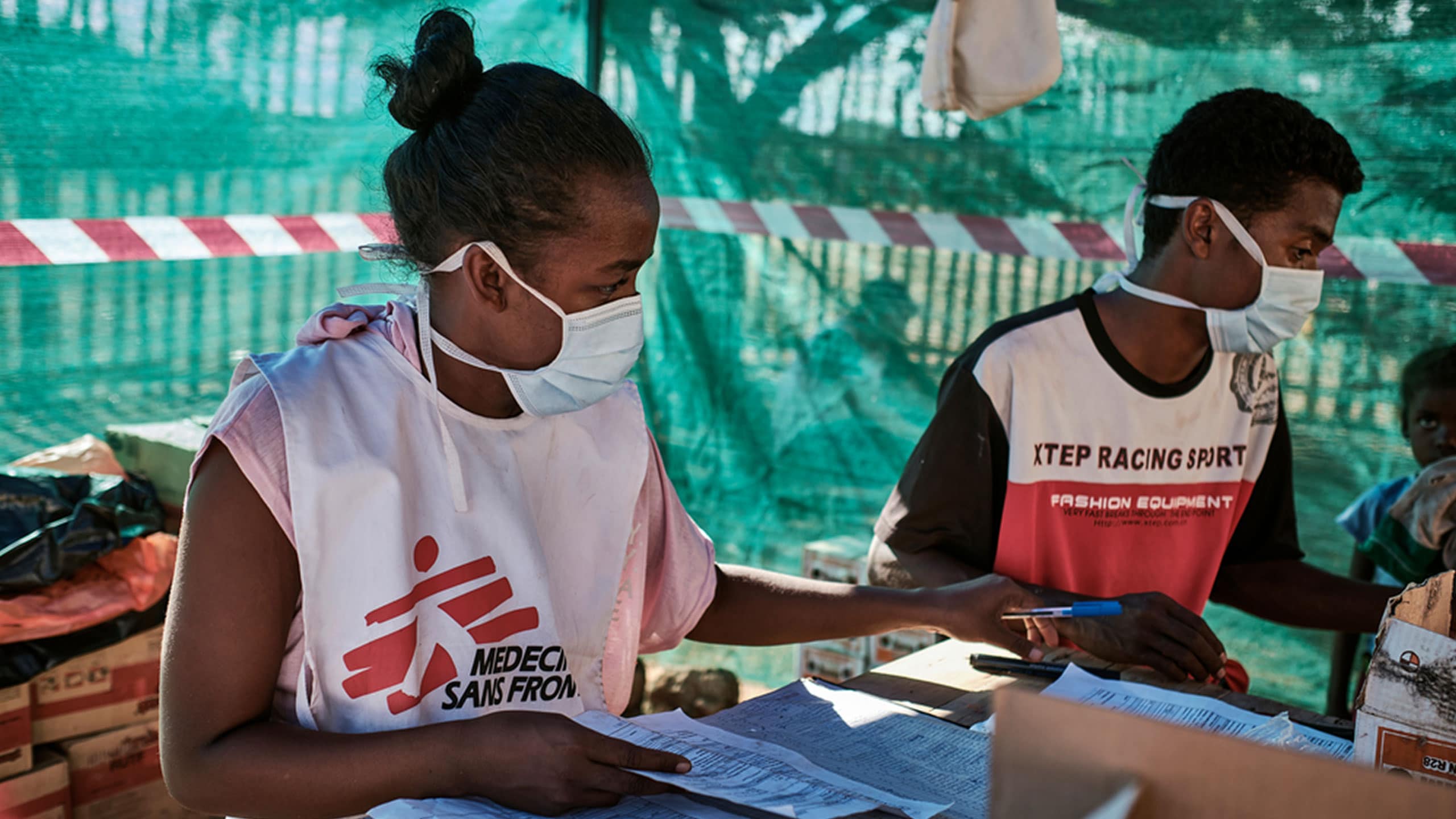 Medecins Sans Frontieres volunteer wearing a mask holding a document