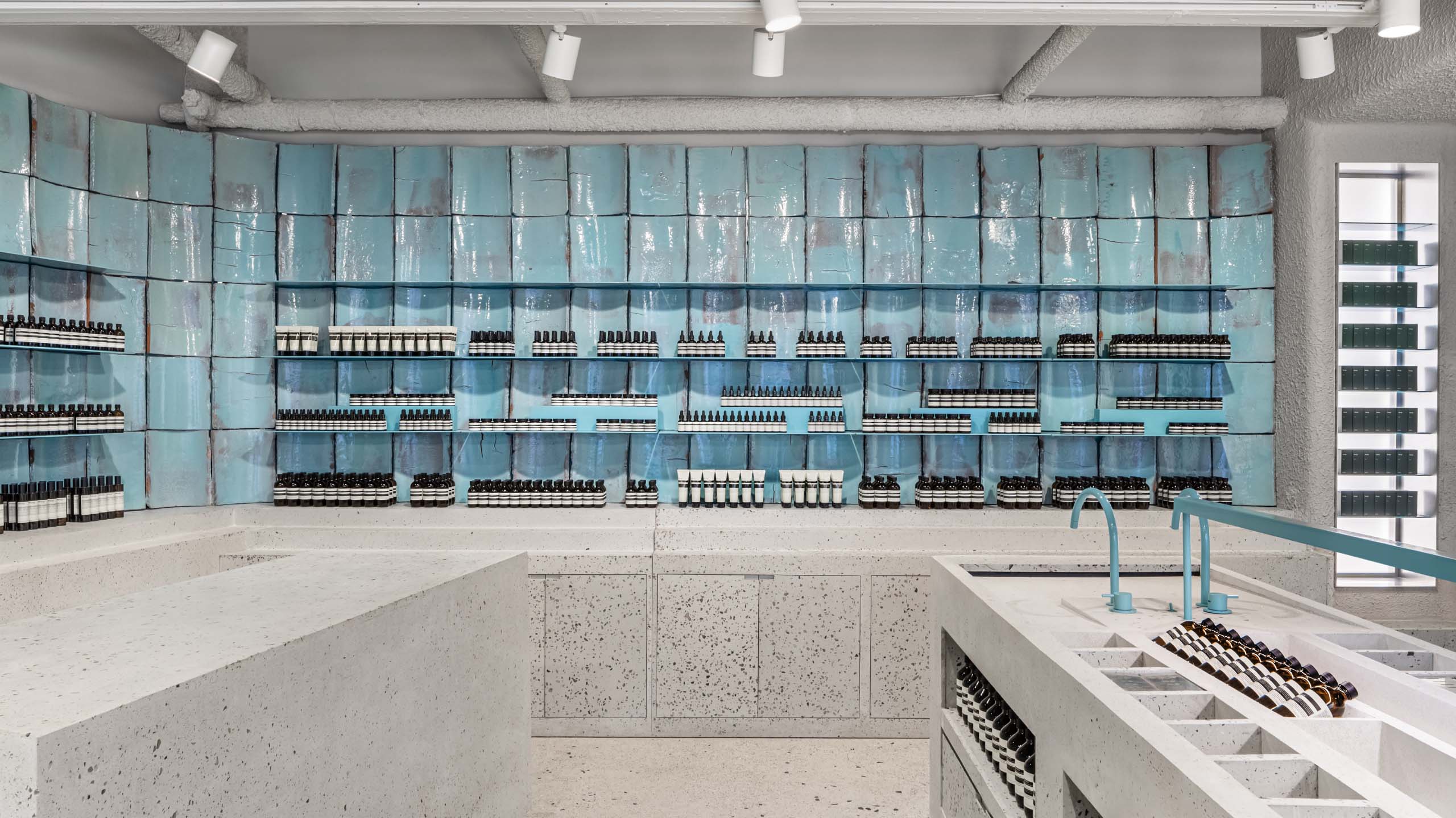 Reclaimed and re-glazed as in blue-green tiles have been presented as exhibits along the back wall with custom-made terrazzo used as the massive counters