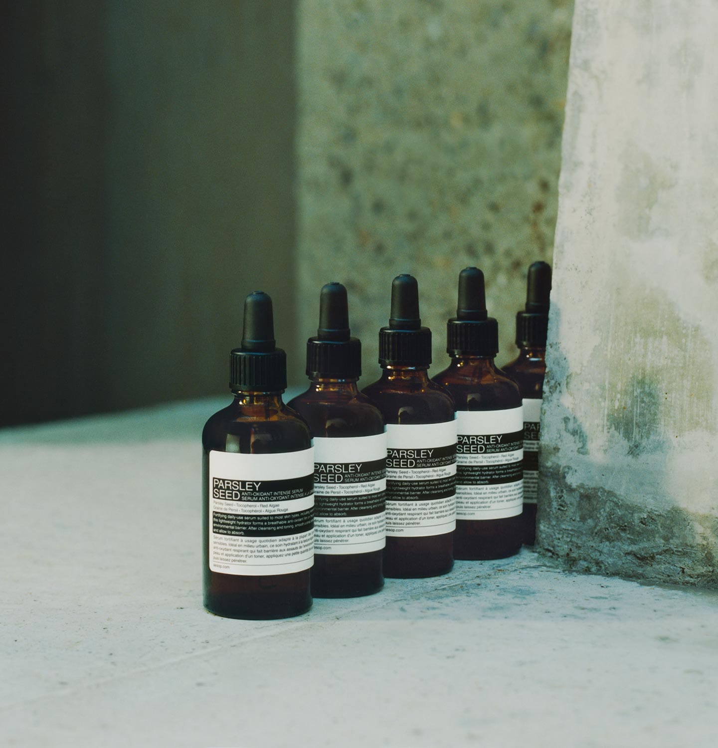 Aesop Parsley Seed Anti-Oxidant Intense Serum bottles lined up next to a concrete wall