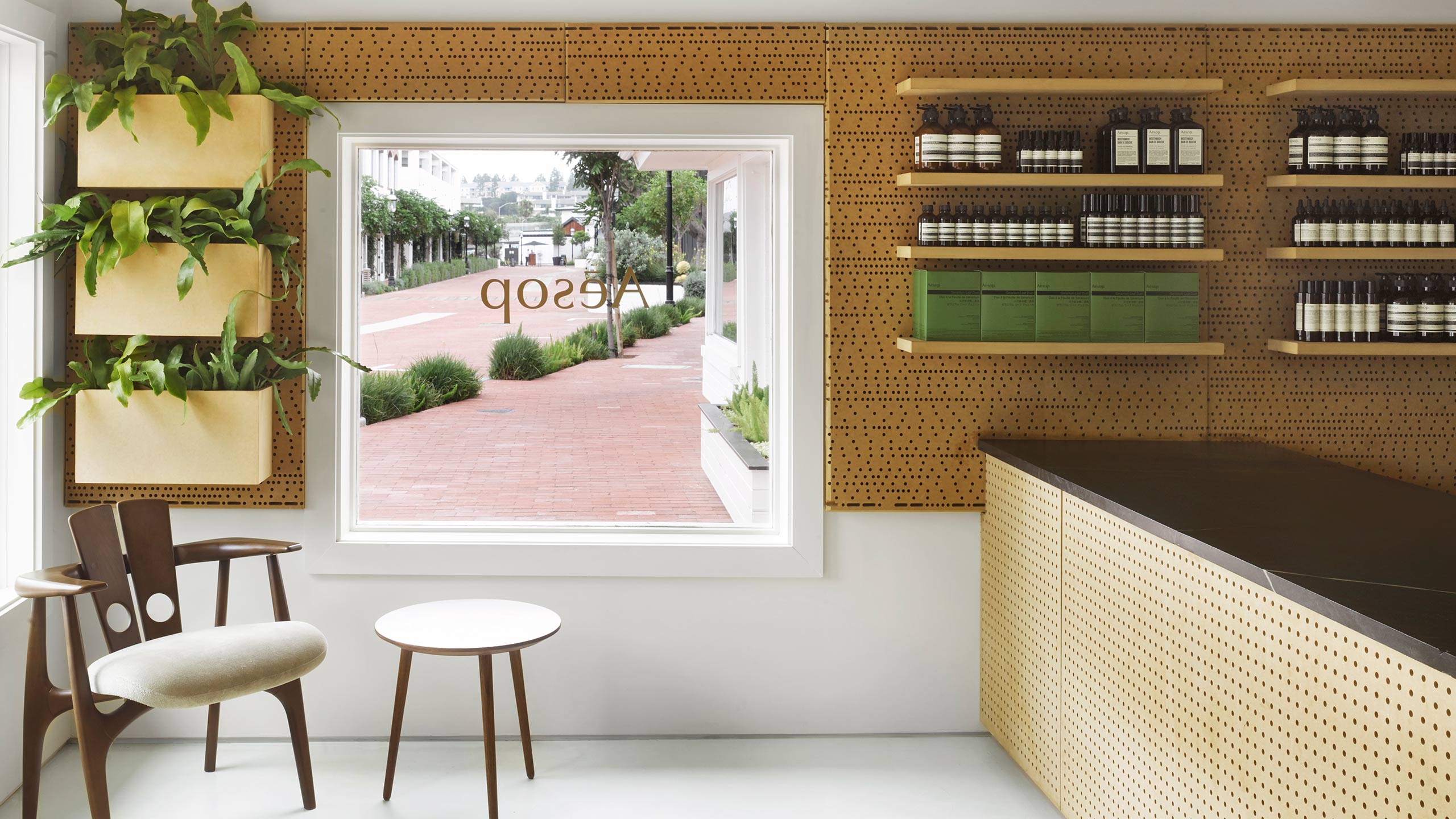 Inside Aesop LIdo Marina, featuring an architectural style chair and table combo, and a window looking out onto the street.