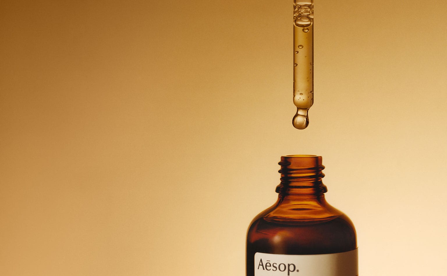 A pipette hovering above an amber glass bottle.