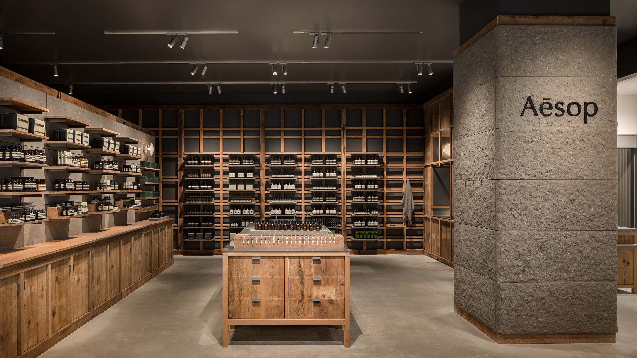 Quartet of inset basins at the central workbench, surrounded with full range of formulations for the skin, hair, body and home on the shelves,  next to the solid blocks of Sapporo Nanseki stone