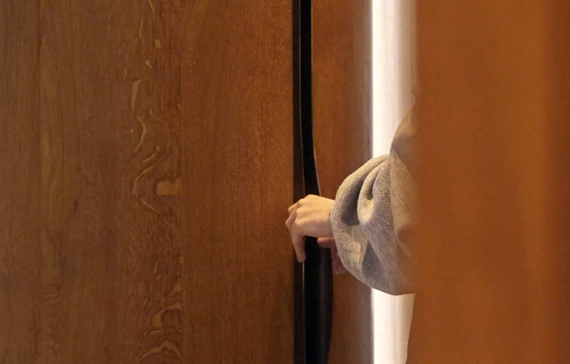 A hand opening a wooden door