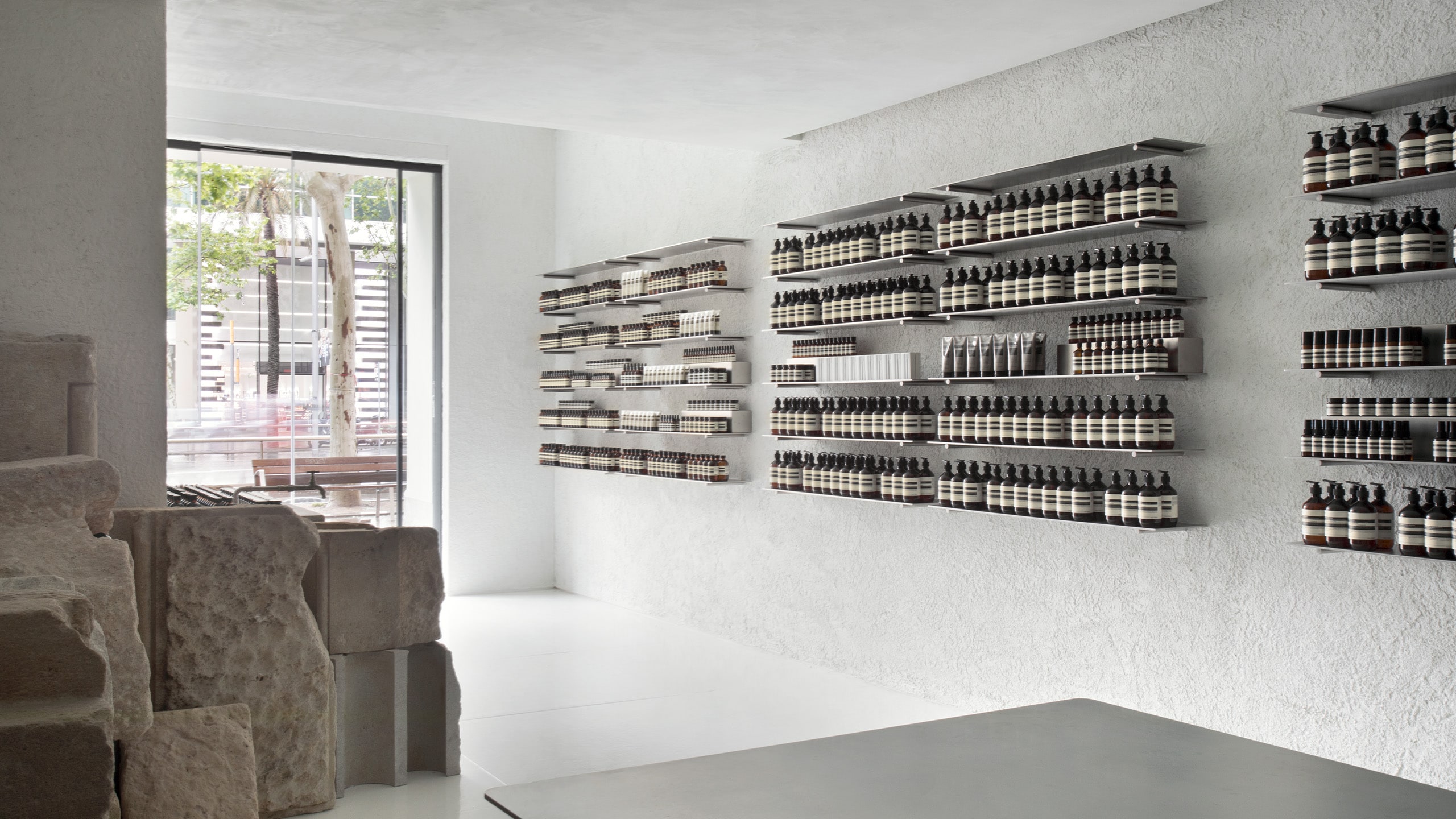 Aesop Diagonal store facade window and rows of product displayed on metal shelving units.