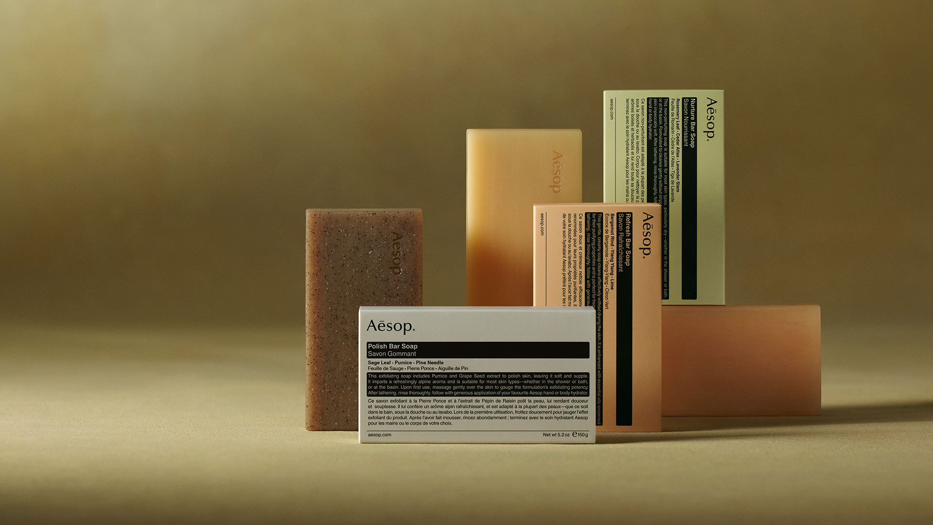 Aesop bar soaps placed next to each other on a green textured background