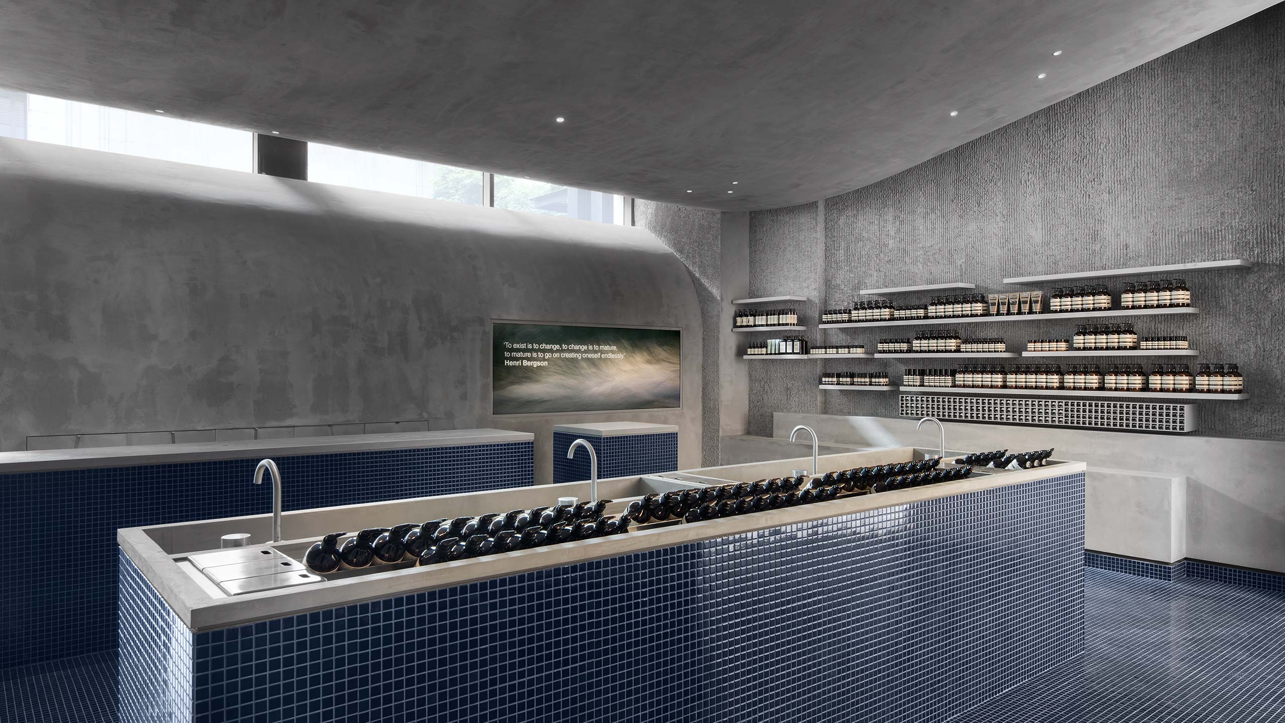 The central customer service basin, with steel fixtures and constructed out of smooth concrete and uniform blue tiles.