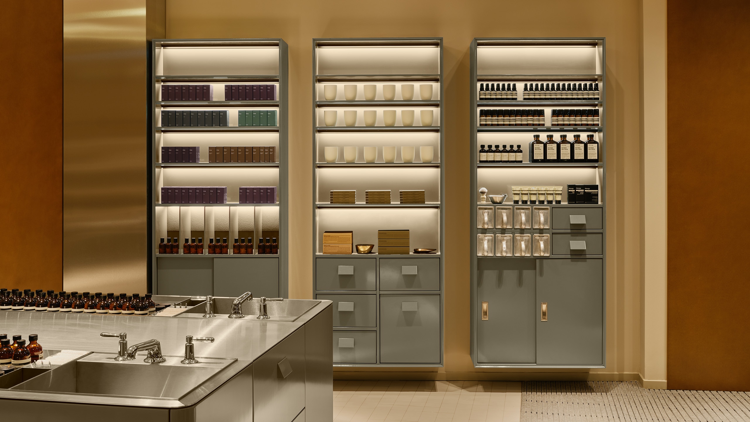 Aesop Sendlinger Strasse store interior metal cabinets and shelves displaying rows of products in amber bottles.