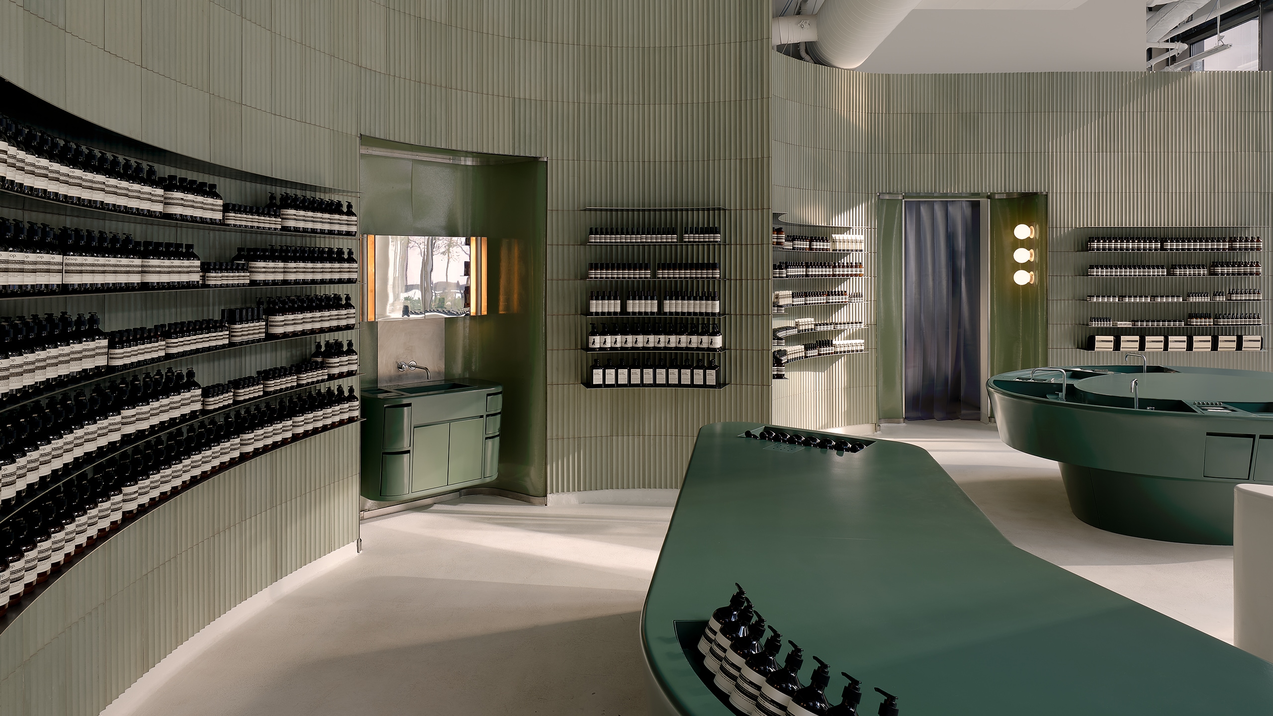 store interior featuring curved grey corrugated walls lined with products on shelves, with green countertop