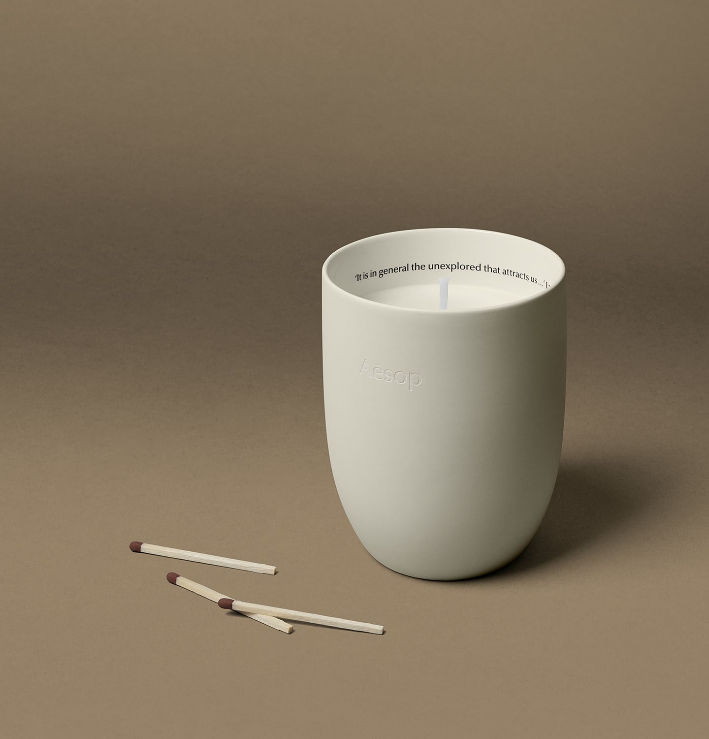 Candle housed in a ceramic vessel, alongside three matchsticks.