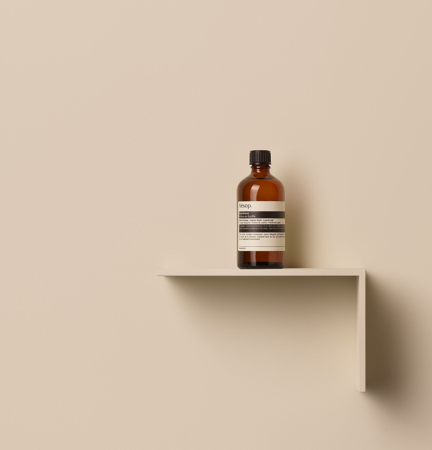 Aesop Breathless in glass amber bottle, placed on a shelf in a beige background