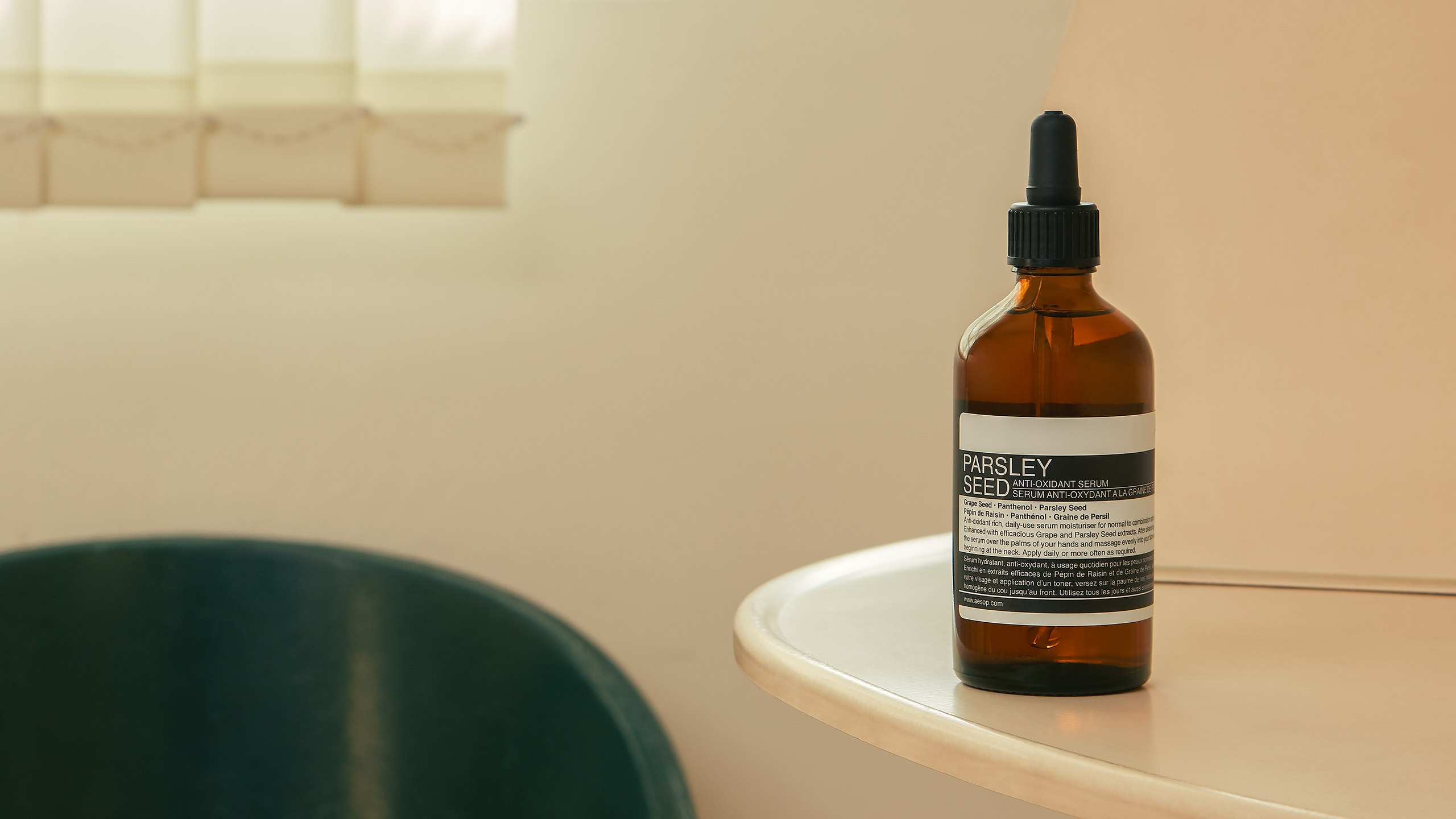 An aesop brown bottle containing serum in a beige background