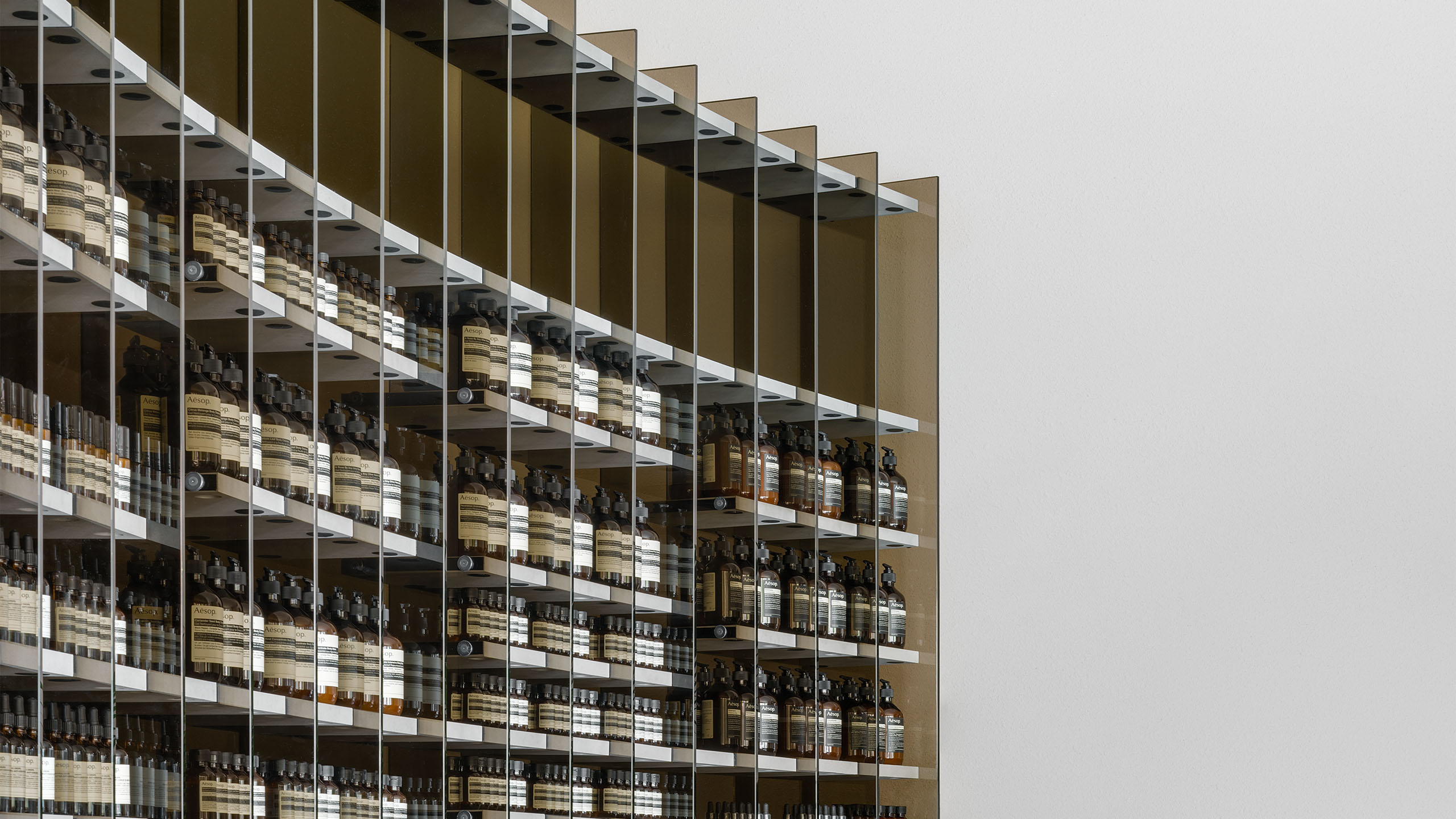 A curved shelving unit of smoked glass runs almost the entire length of the left wall.