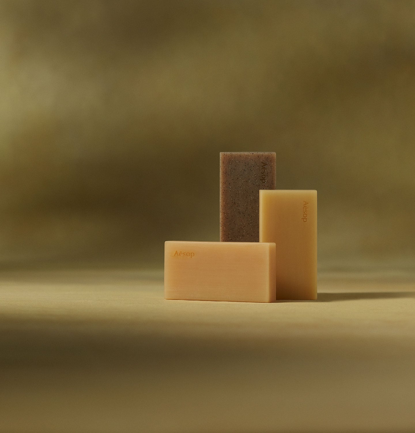 Aesop Bar soaps placed  in front of dark yellow textured background