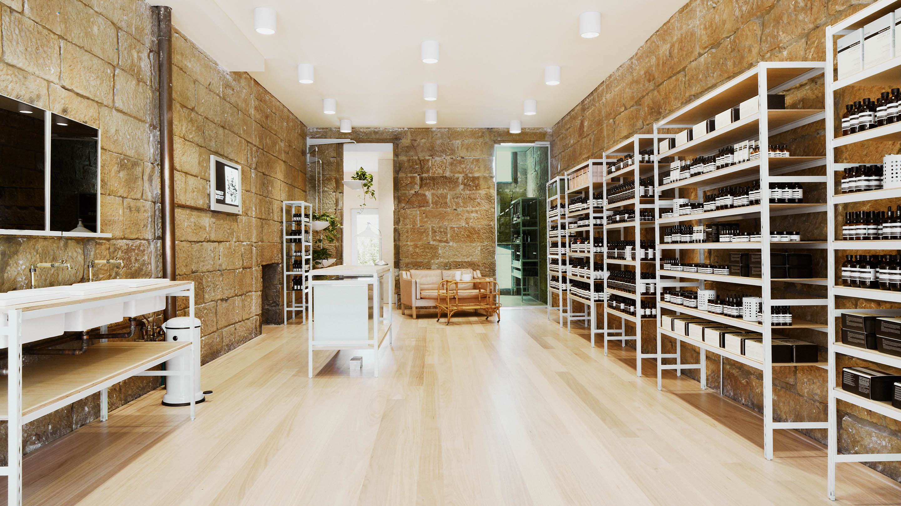 A long narrow store interior, white metal shelving lines the walls, that are constructed from large stone brick.