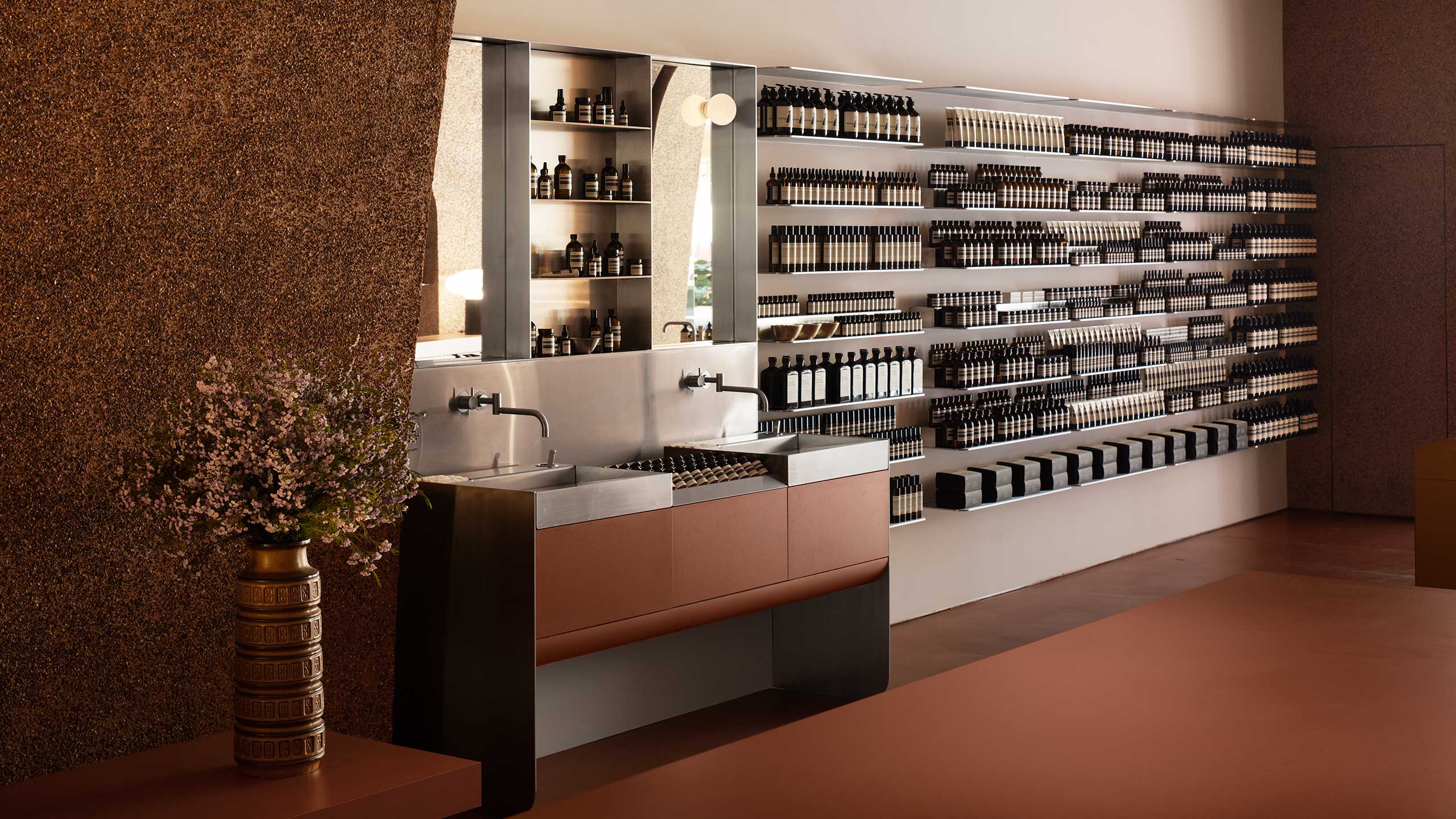 Aesop Southland interior with vase and sink next to shelves displaying Aesop products