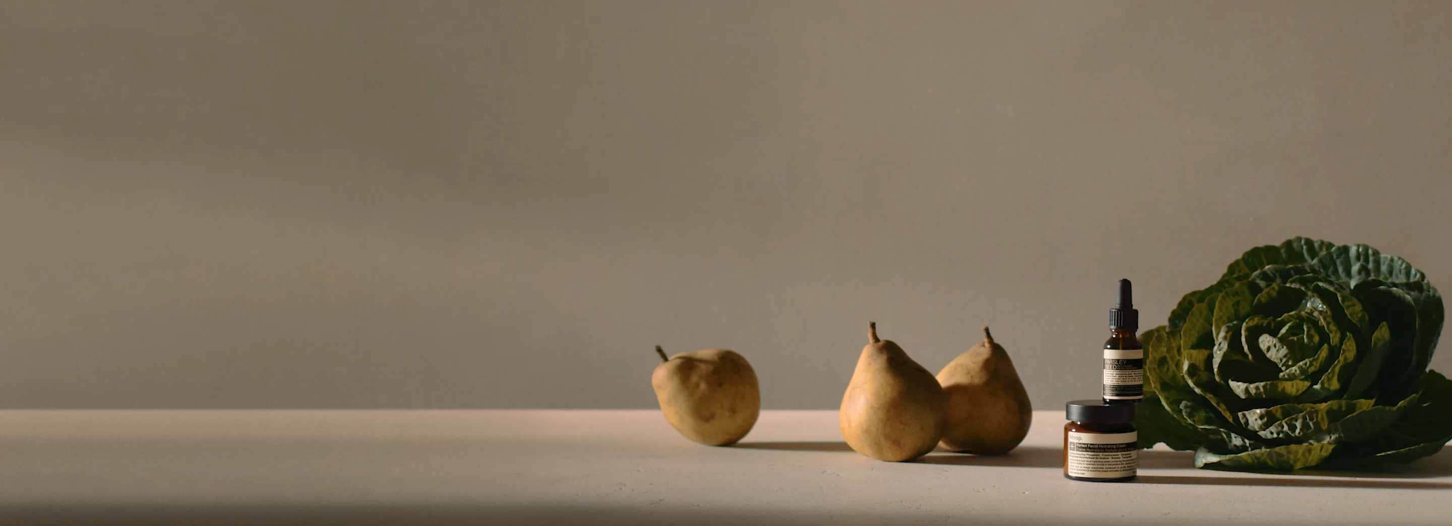 Two amber glass jars sitting next to a cabbage leaf and three pears.