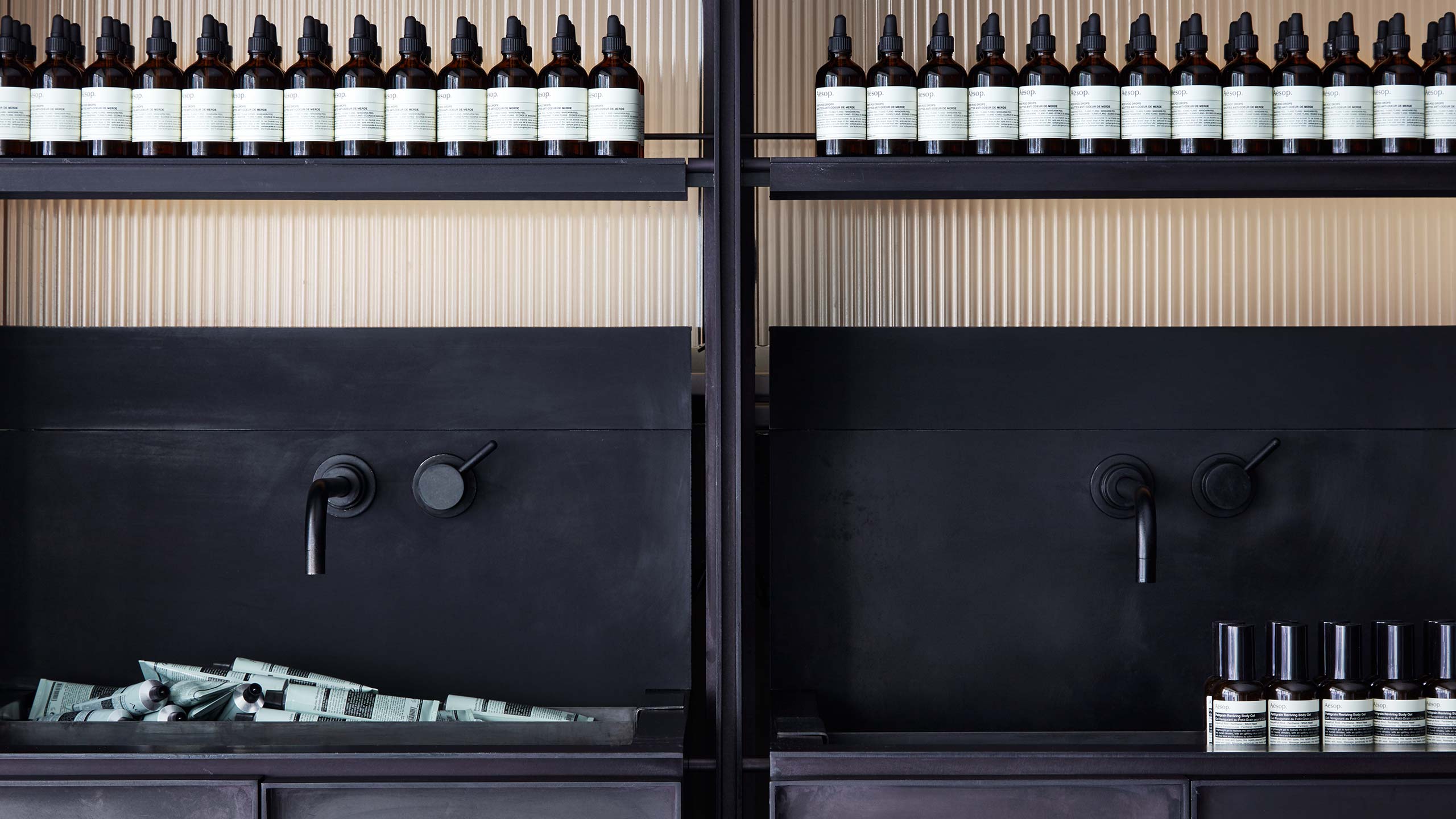 A modern steel black sink with Aesop home products. 