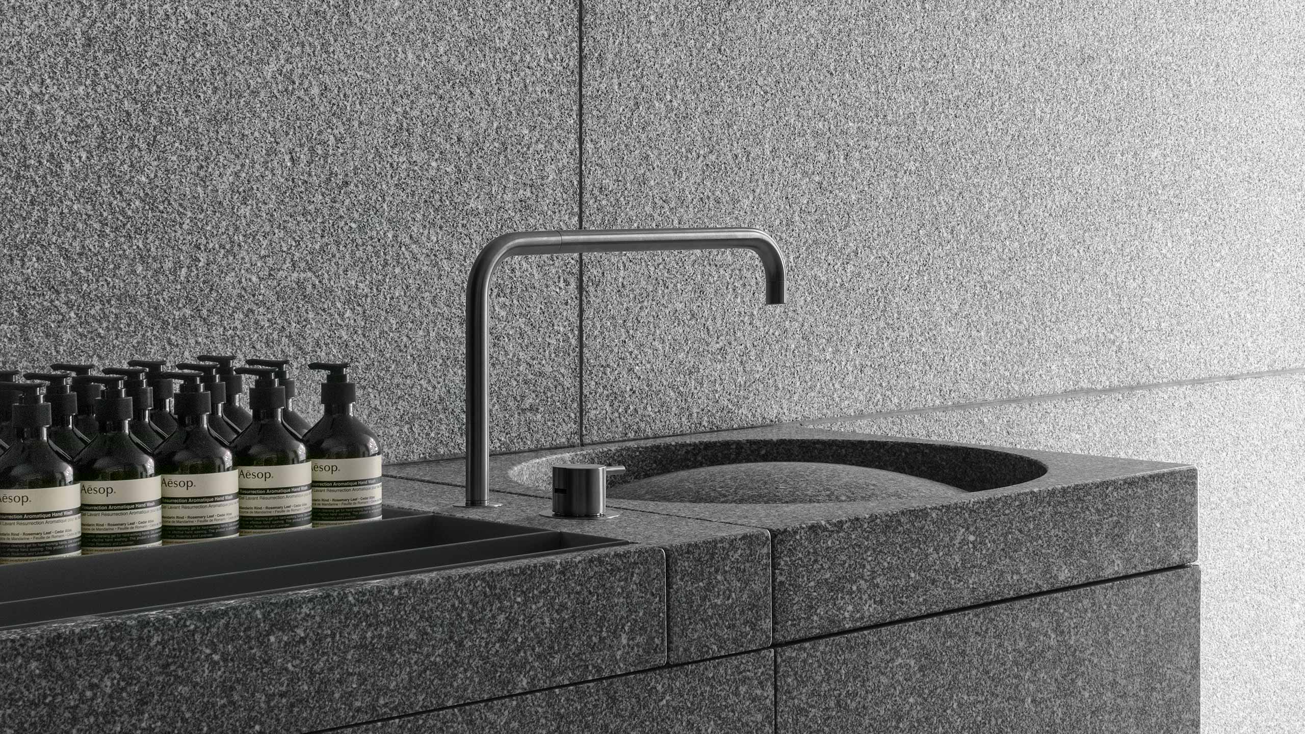 Textured surface details of concrete wall and steel sink.