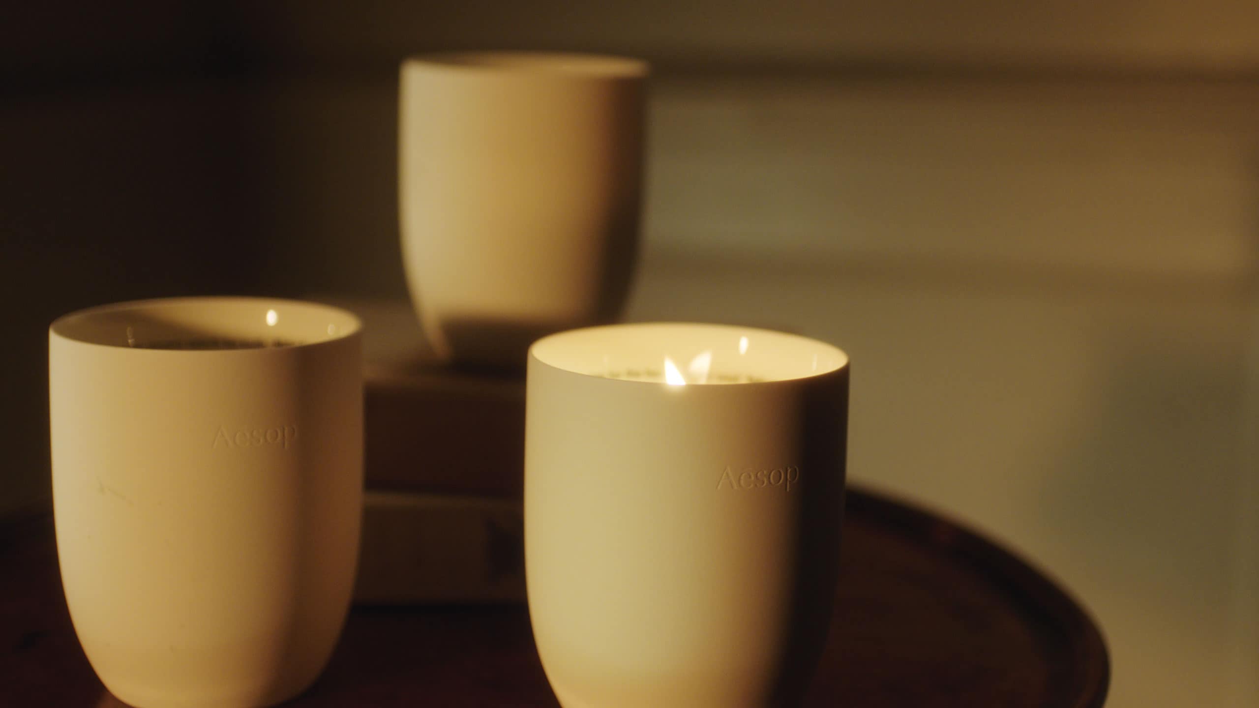 Three of Aesop's Aromatique Candles, burning.
