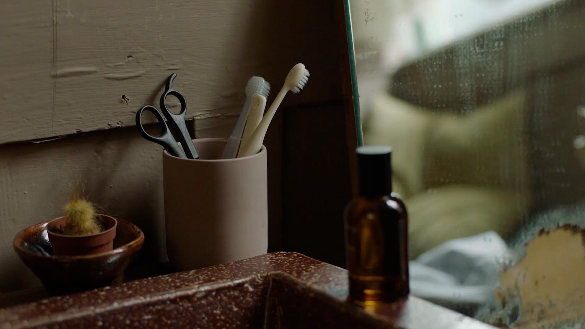 An amber glass bottle of Eidesis Eau de Parfum sitting on the ridge of a basin.