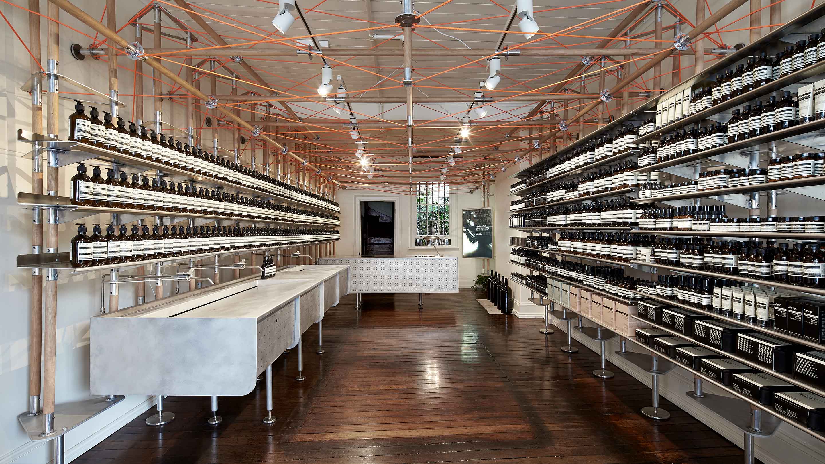 Displaying an industrial interior, with a steel basin off to one side, with the store counter at the end. The interior is flanked by shelving on either side. 