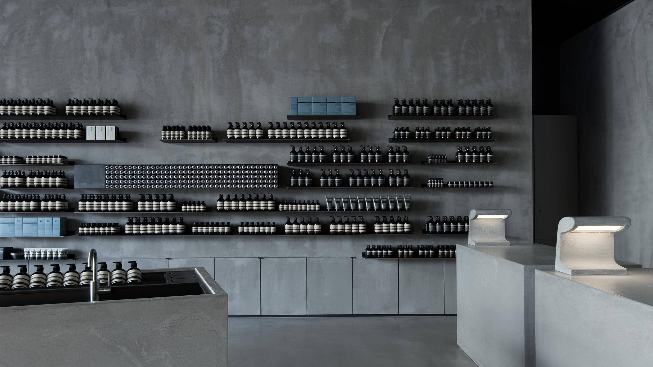 Grey concrete counters are on the right, with bespoke concrete lamps. On the left, a deep concrete basin.
